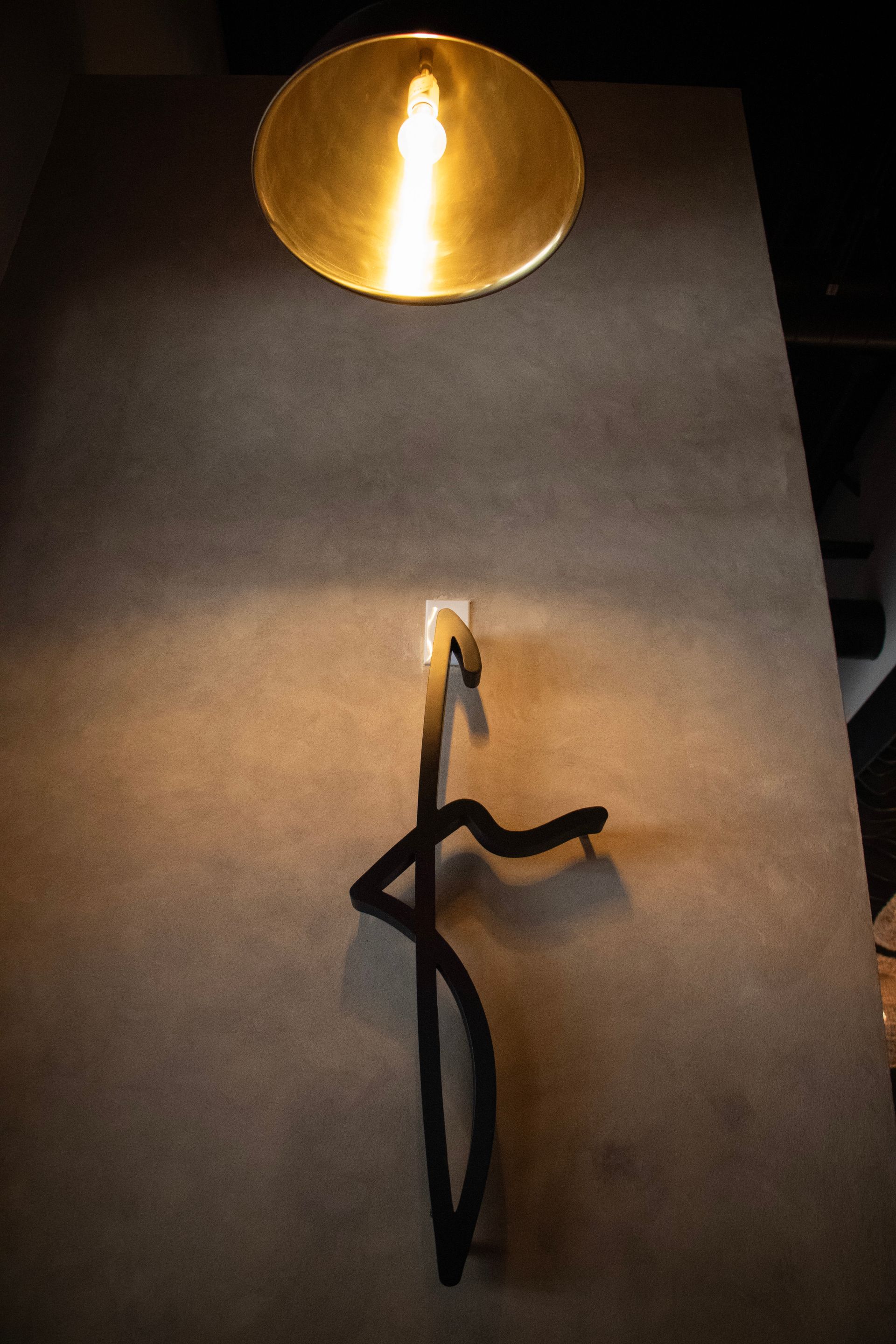 A candle is lit up under a lamp on a table.