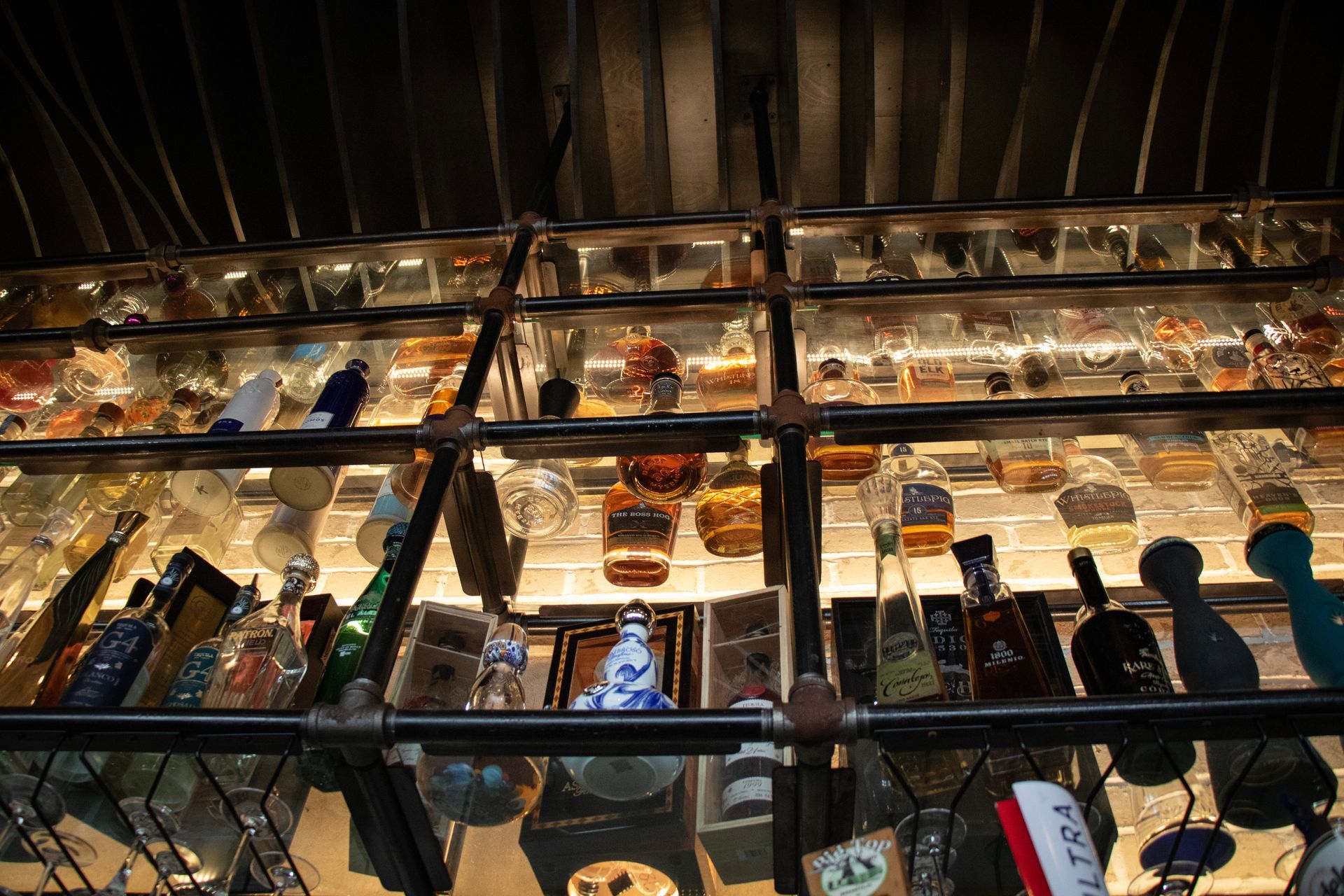 Bottles of alcohol are lined up on a glass shelf