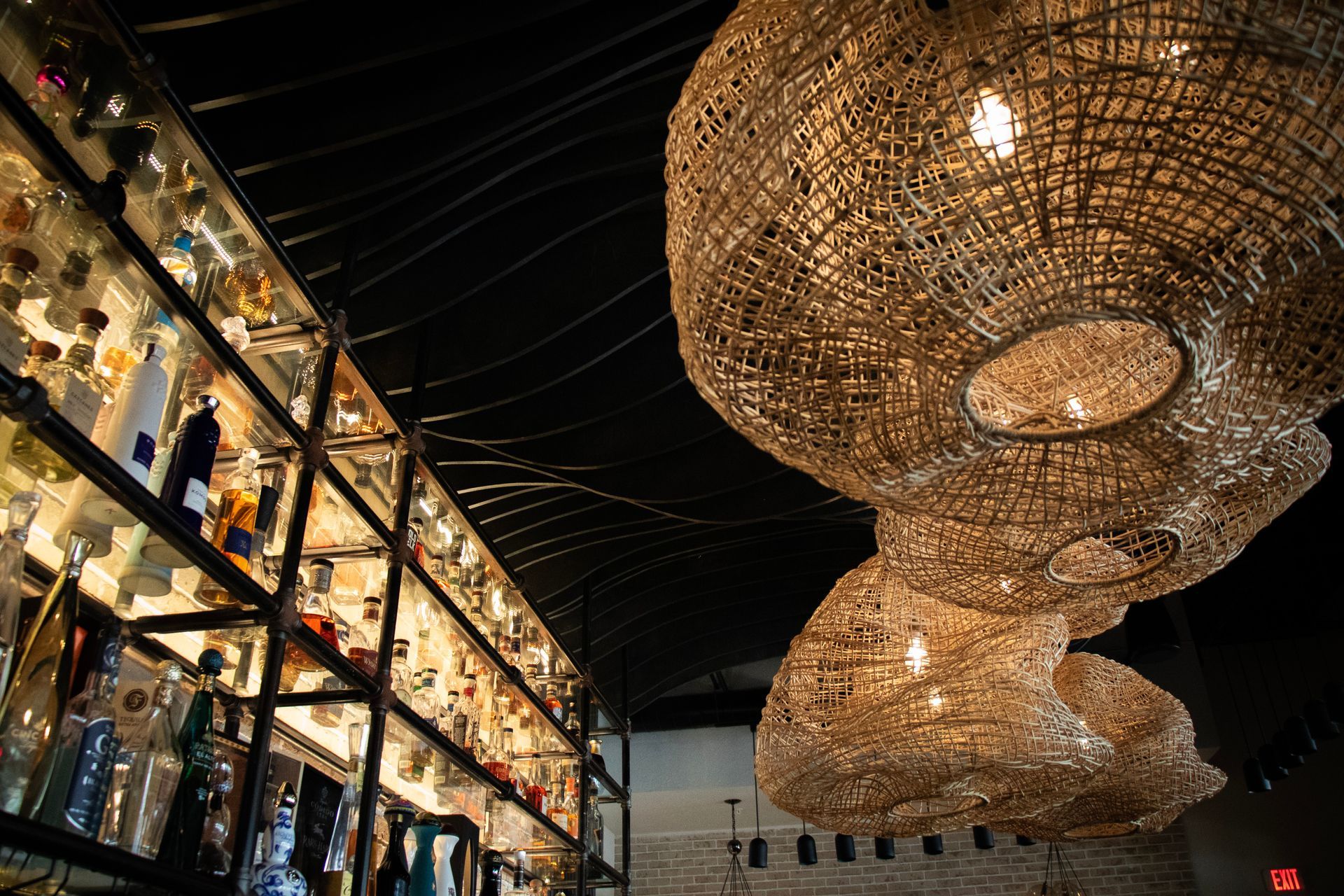 A bar with a lot of bottles on shelves and a lot of lights hanging from the ceiling.
