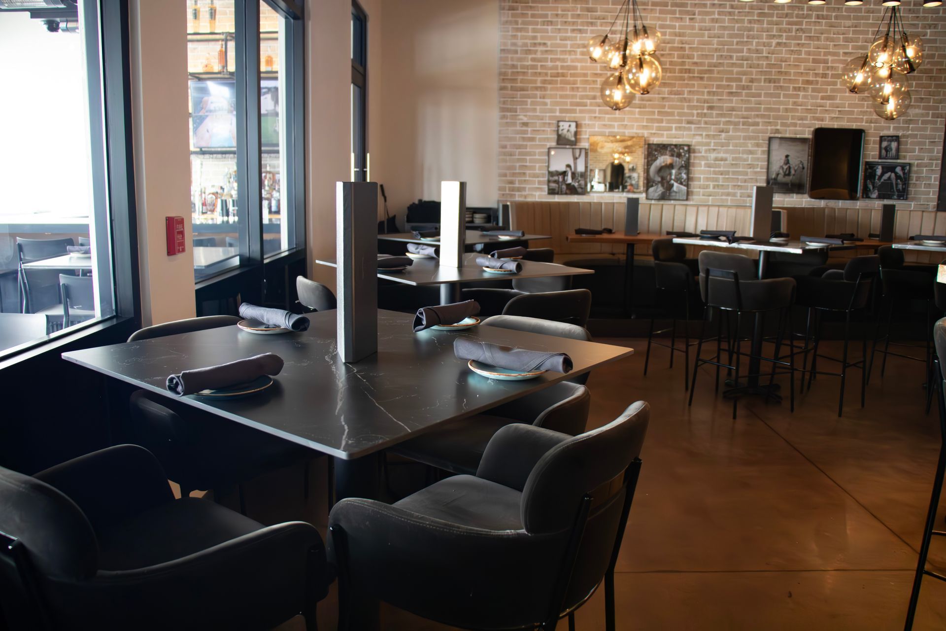A restaurant with tables and chairs and a brick wall.