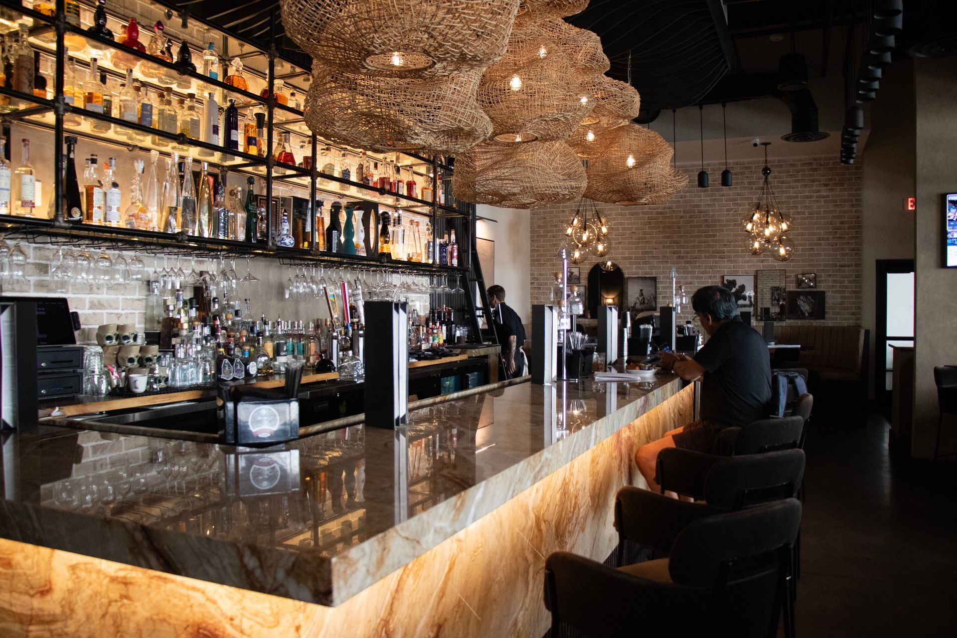 A man is sitting at a bar in a restaurant.