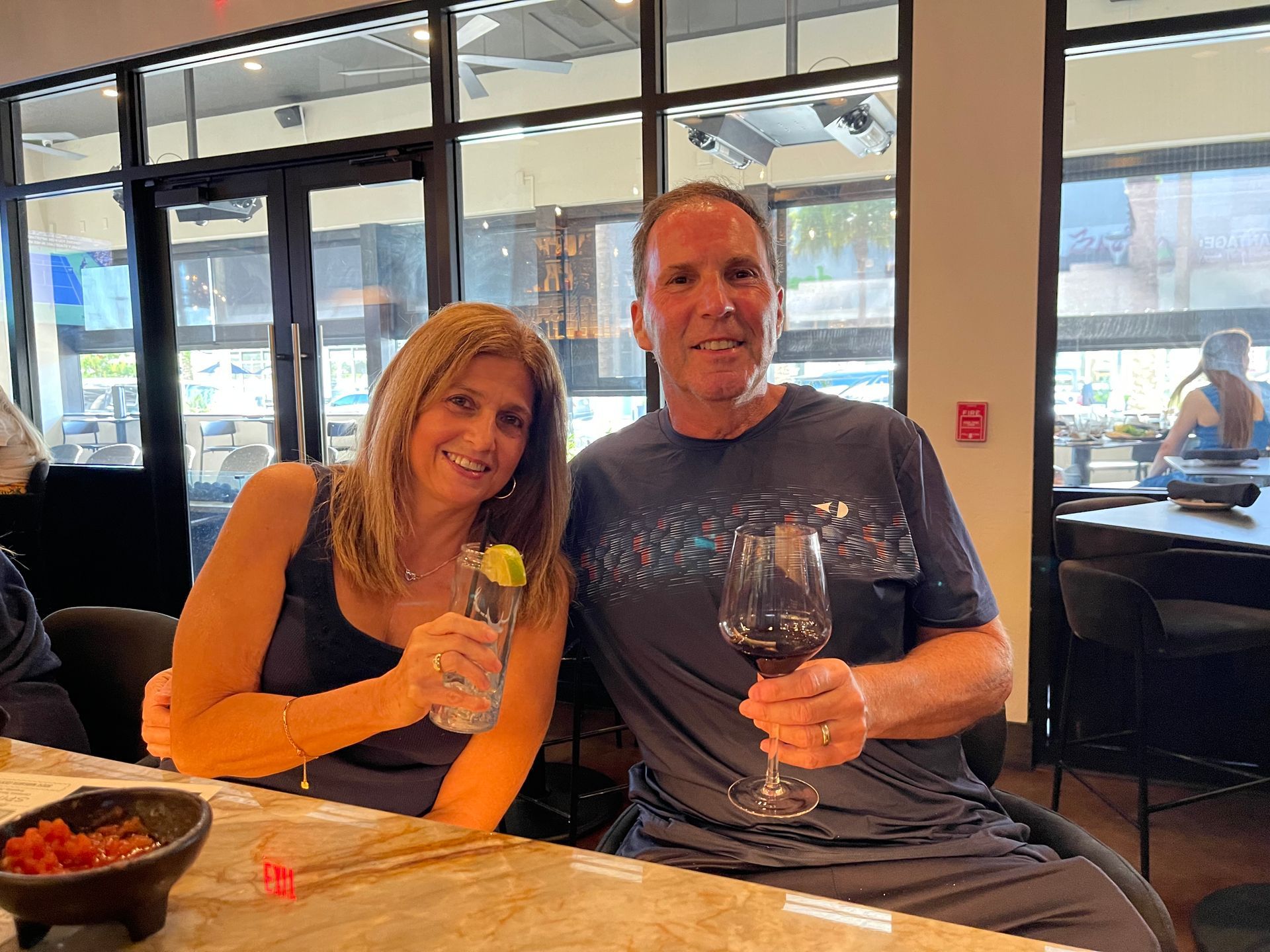 A man and a woman are sitting at a table holding wine glasses.