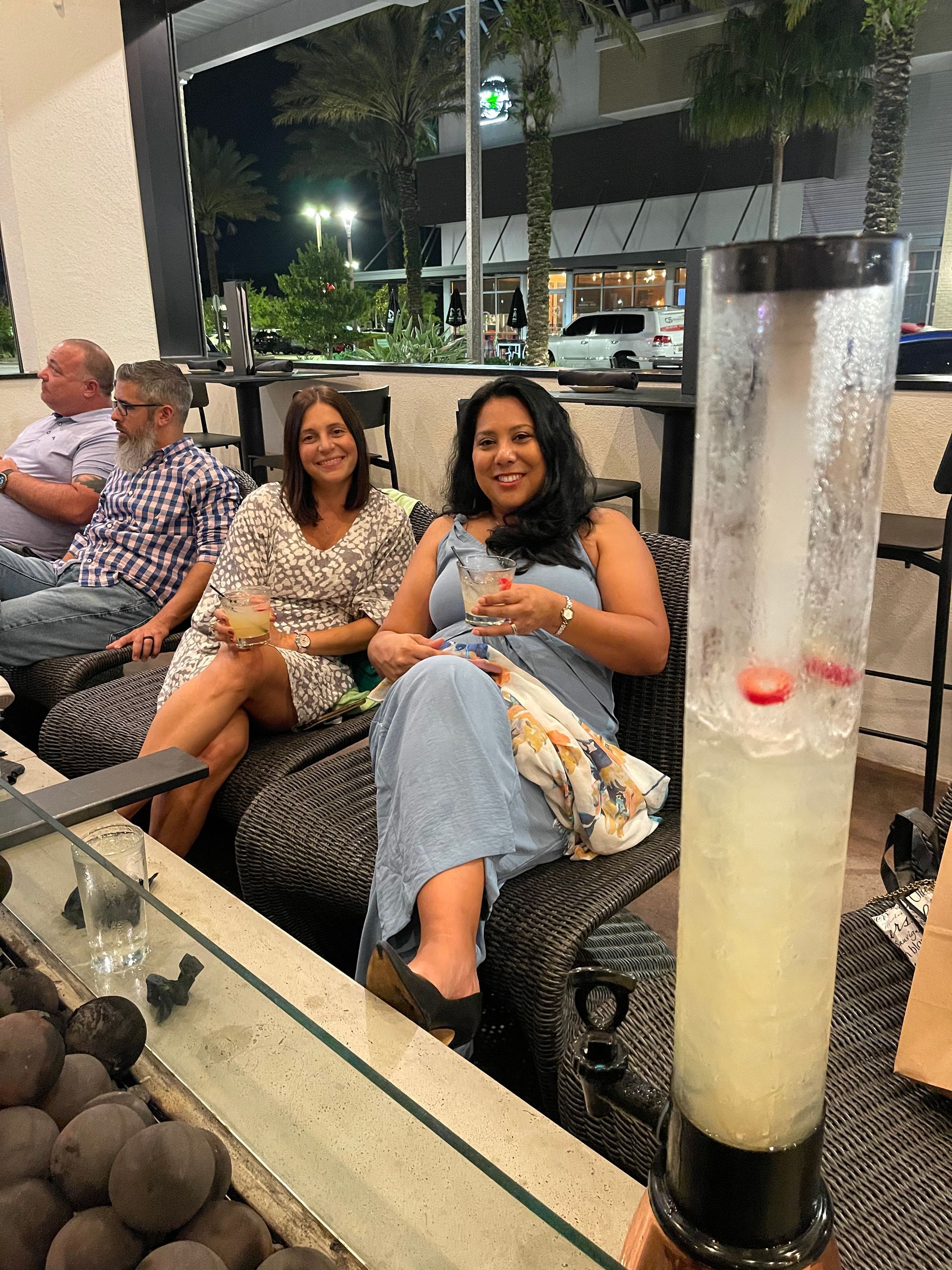 A group of people are sitting on a couch with drinks.