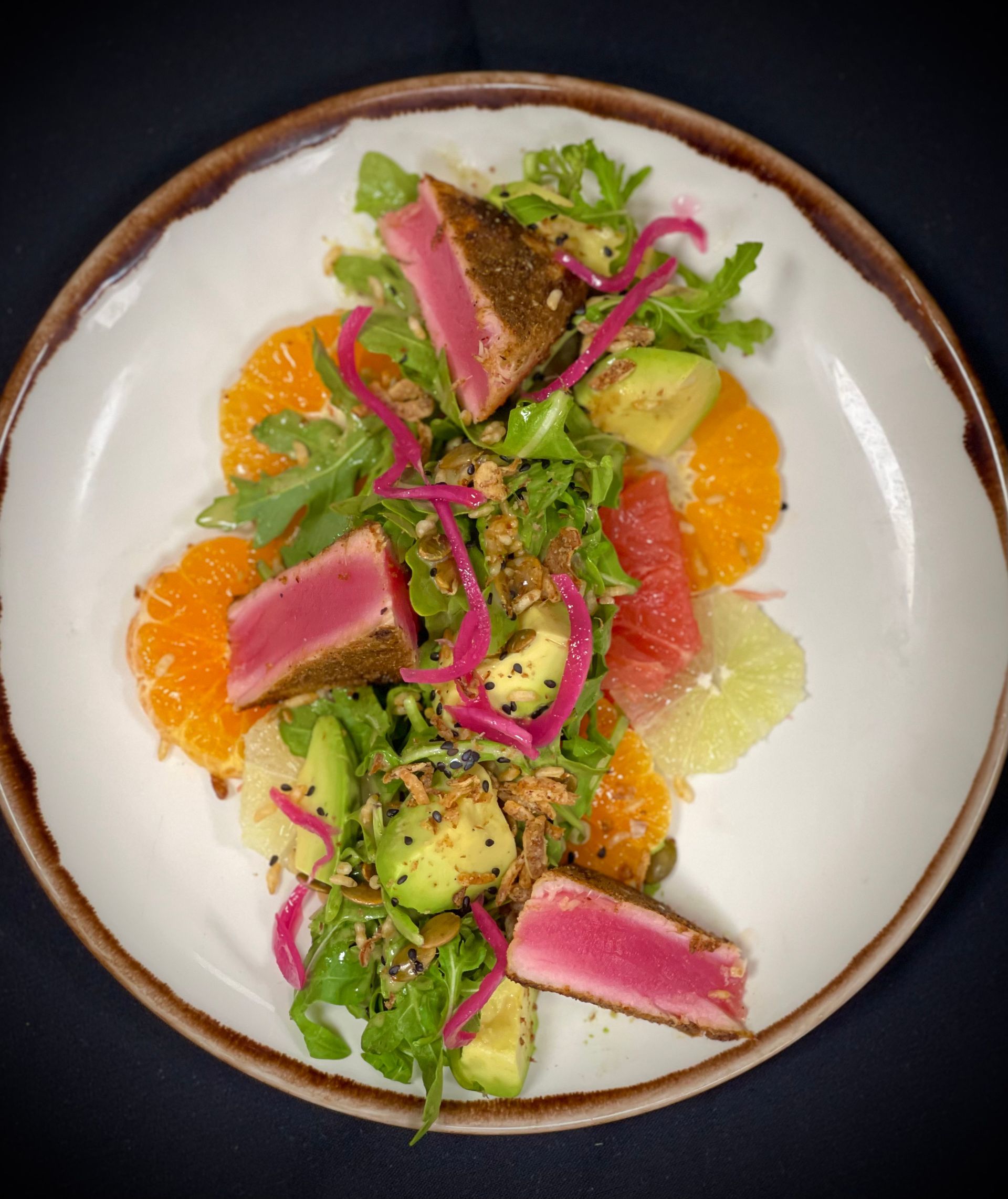 A white plate topped with a salad of meat and vegetables