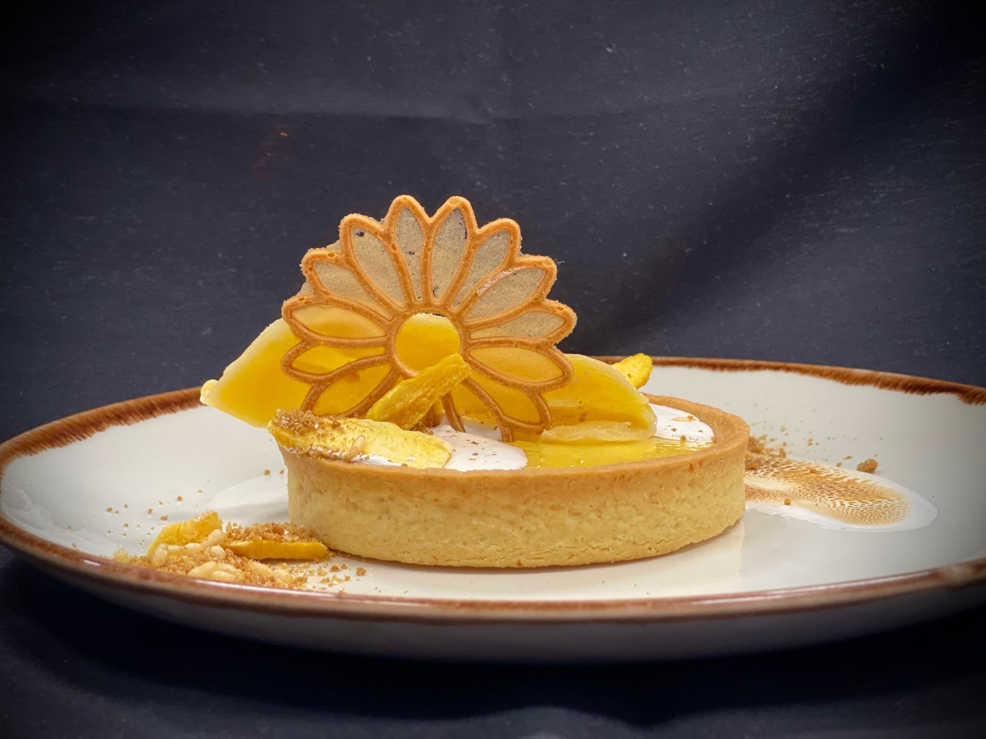 A dessert on a white plate with a yellow flower on top