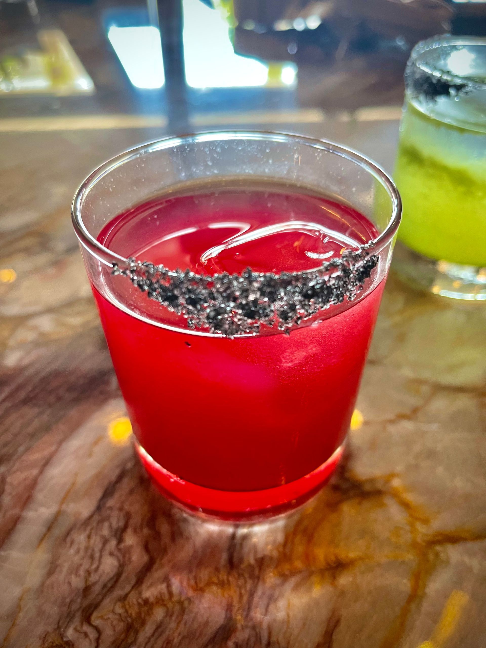 A close up of a red drink in a glass on a table.