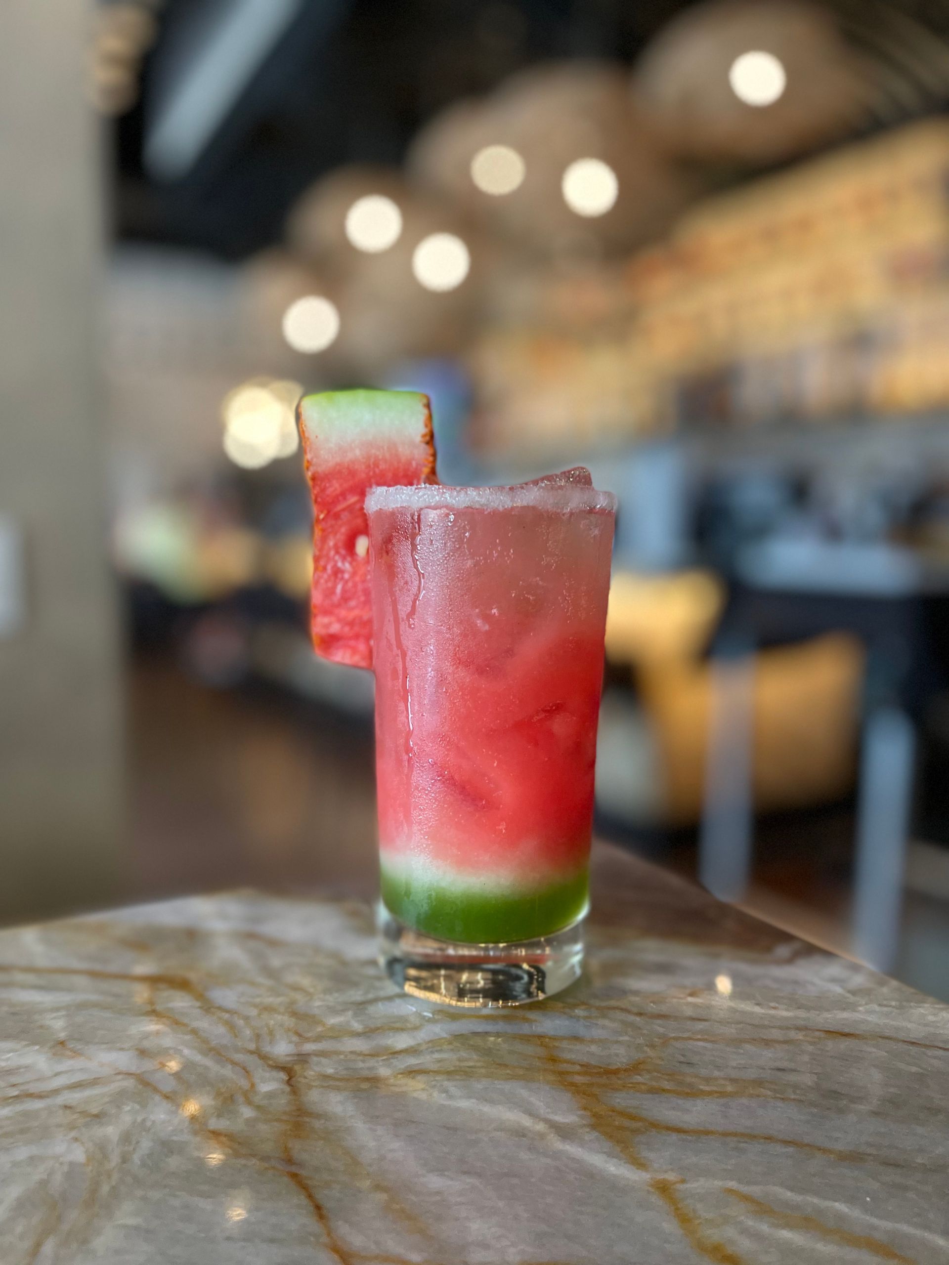 A watermelon drink in a tall glass on a table.