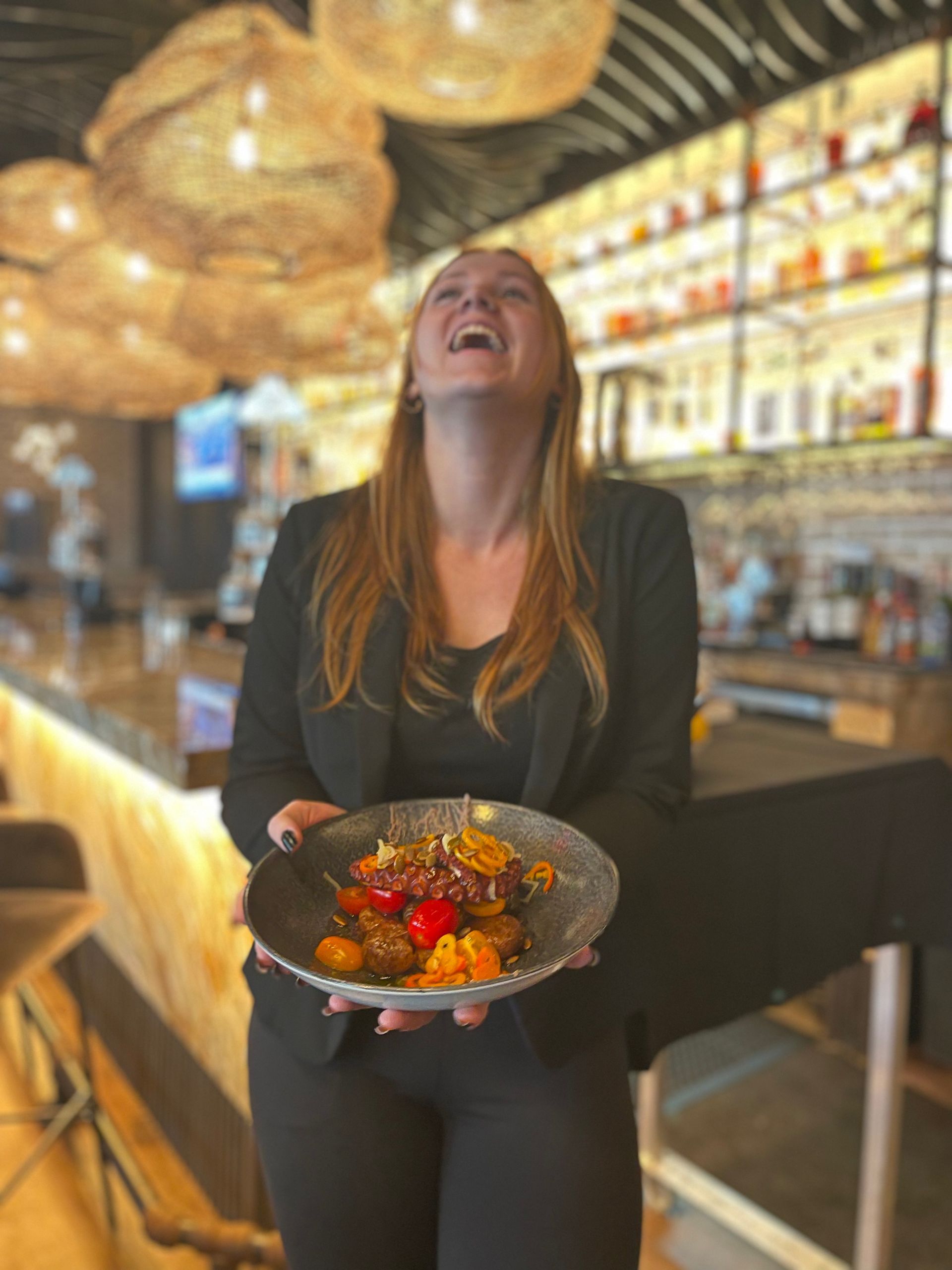 A woman is holding a plate of food in a restaurant.