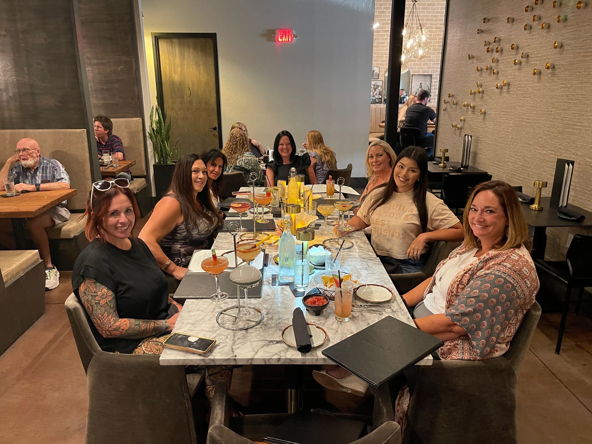 A group of people are sitting at a long table in a restaurant.
