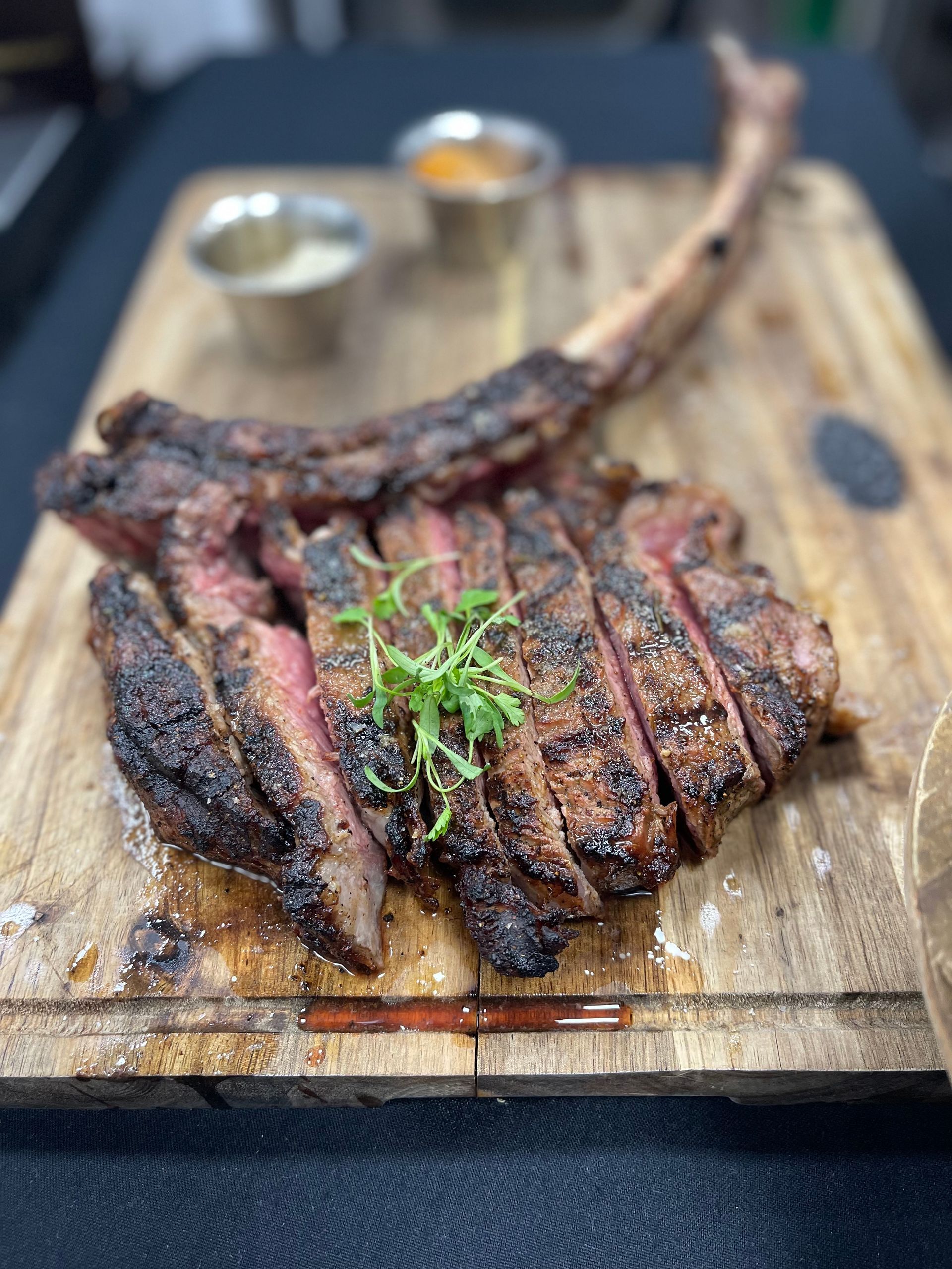 A large steak is sitting on top of a wooden cutting board.