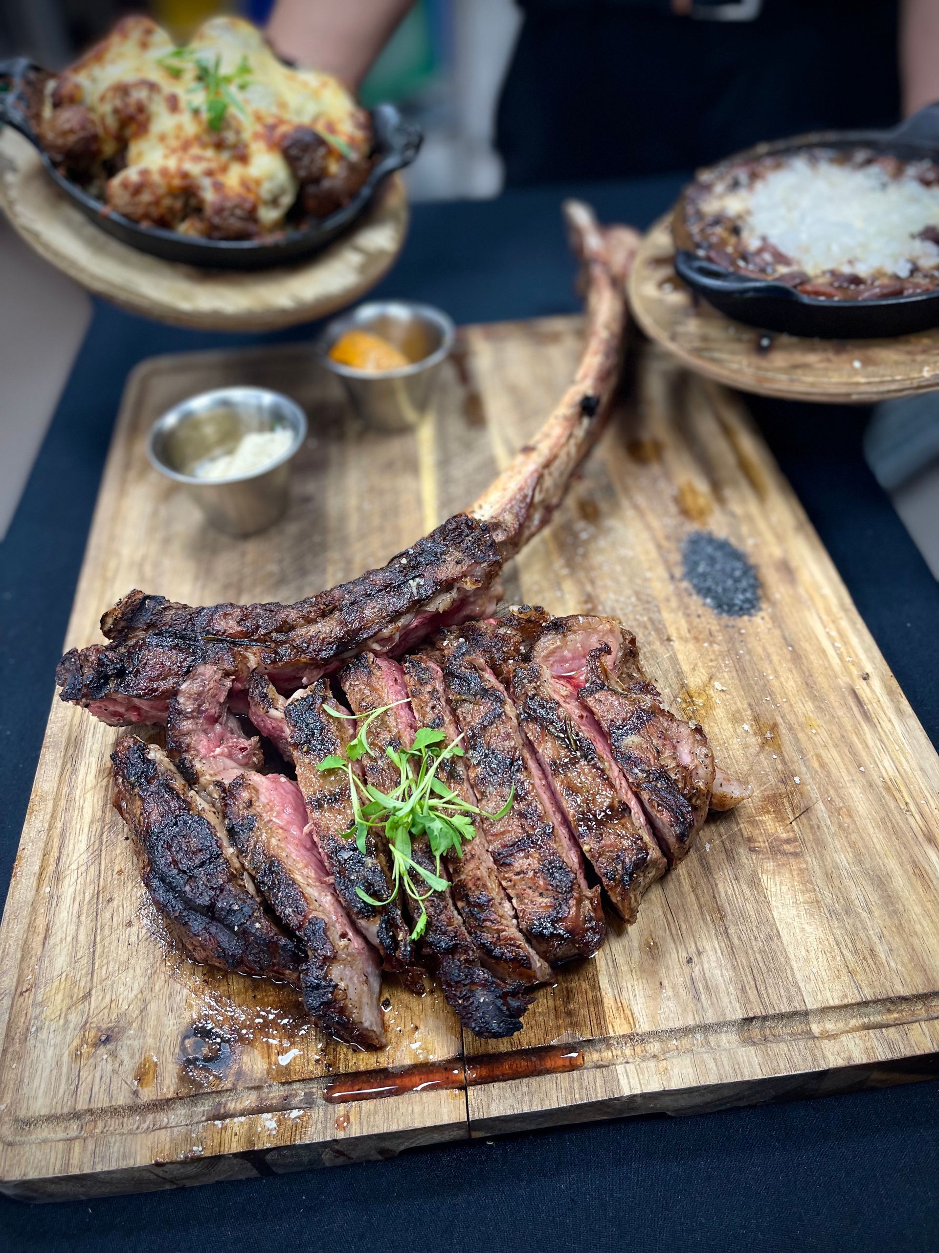 A large steak is sitting on top of a wooden cutting board.
