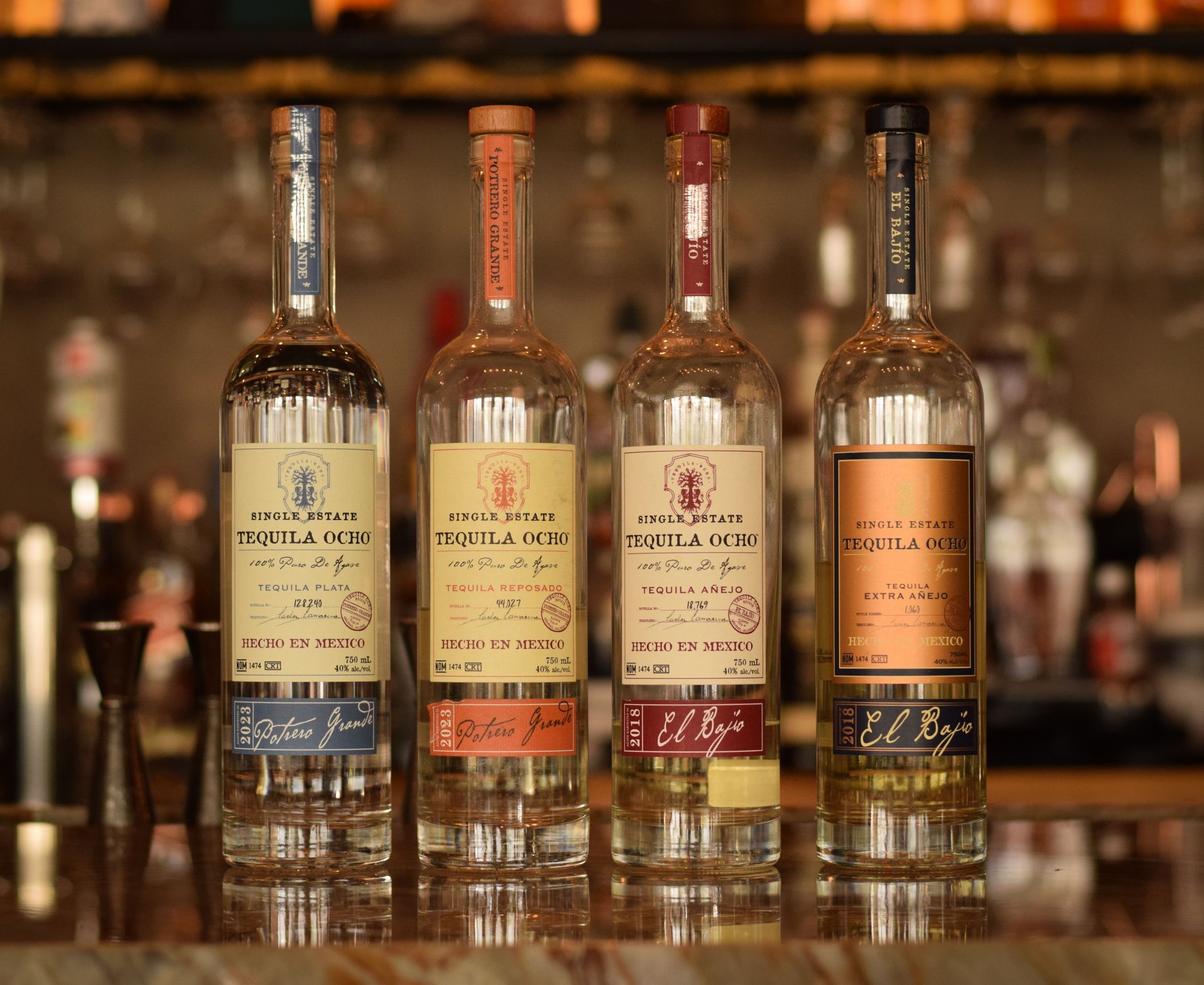 Four bottles of tequila are lined up on a bar
