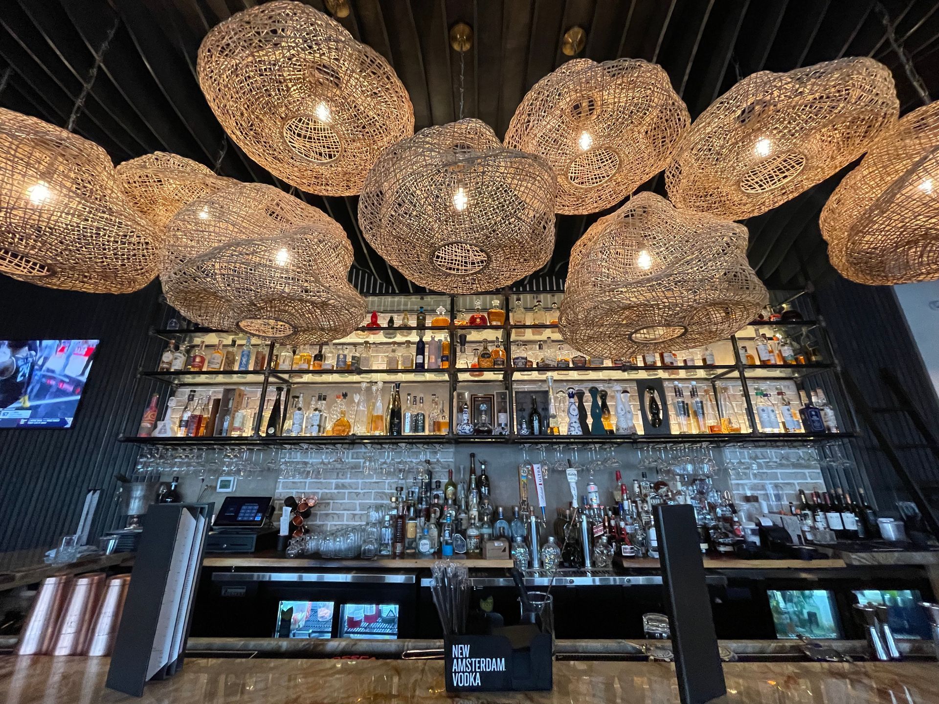 A bar with a lot of bottles on it and a lot of lights hanging from the ceiling.