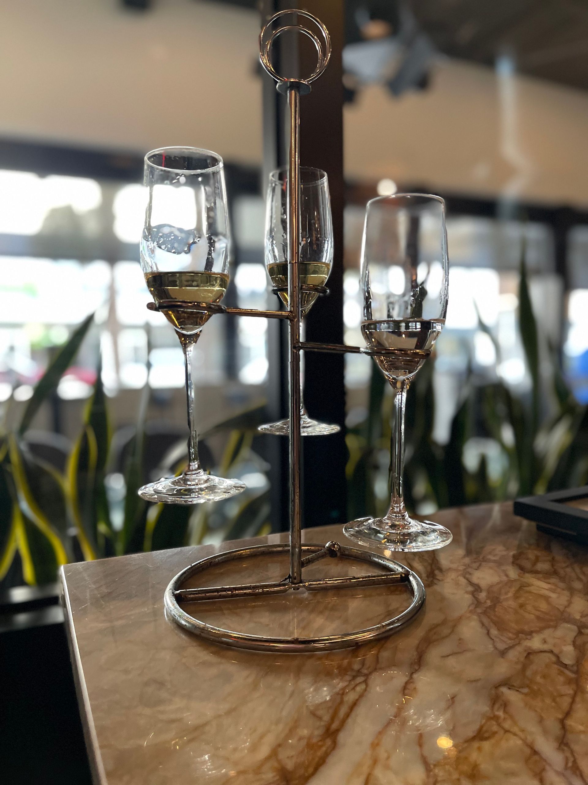Three wine glasses are on a stand on a table