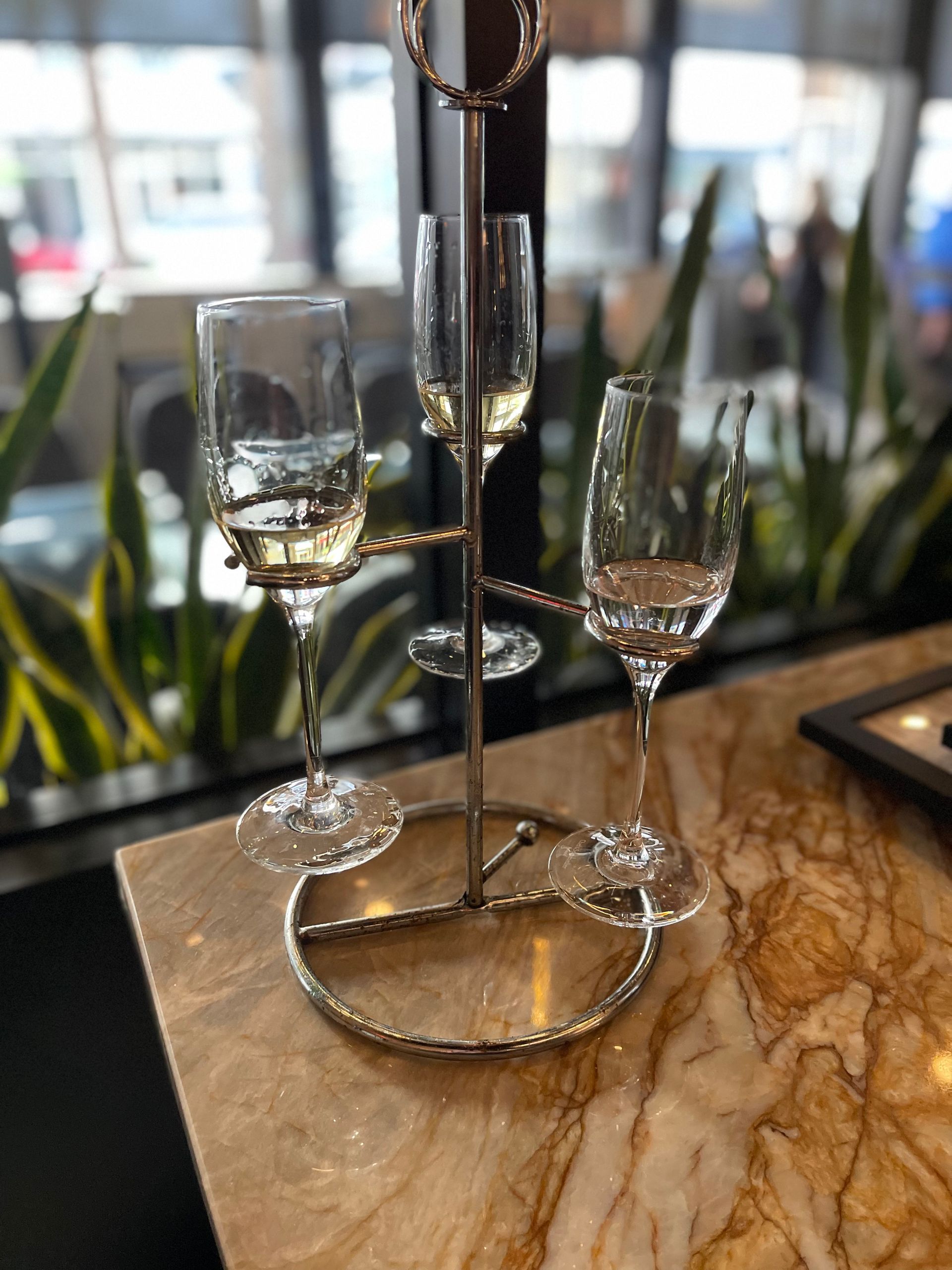 Three wine glasses on a stand on a table
