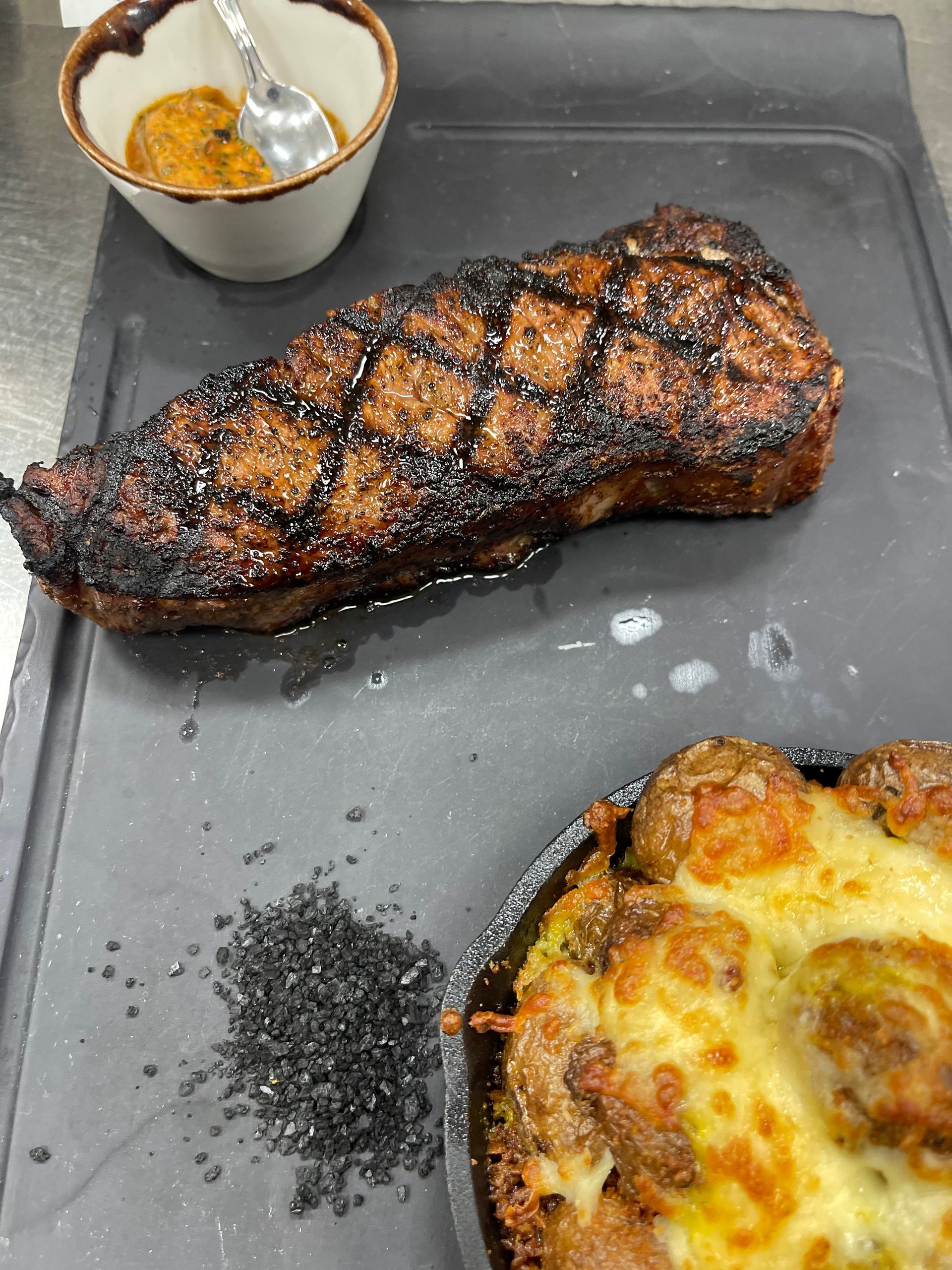 A steak and a pizza are on a cutting board