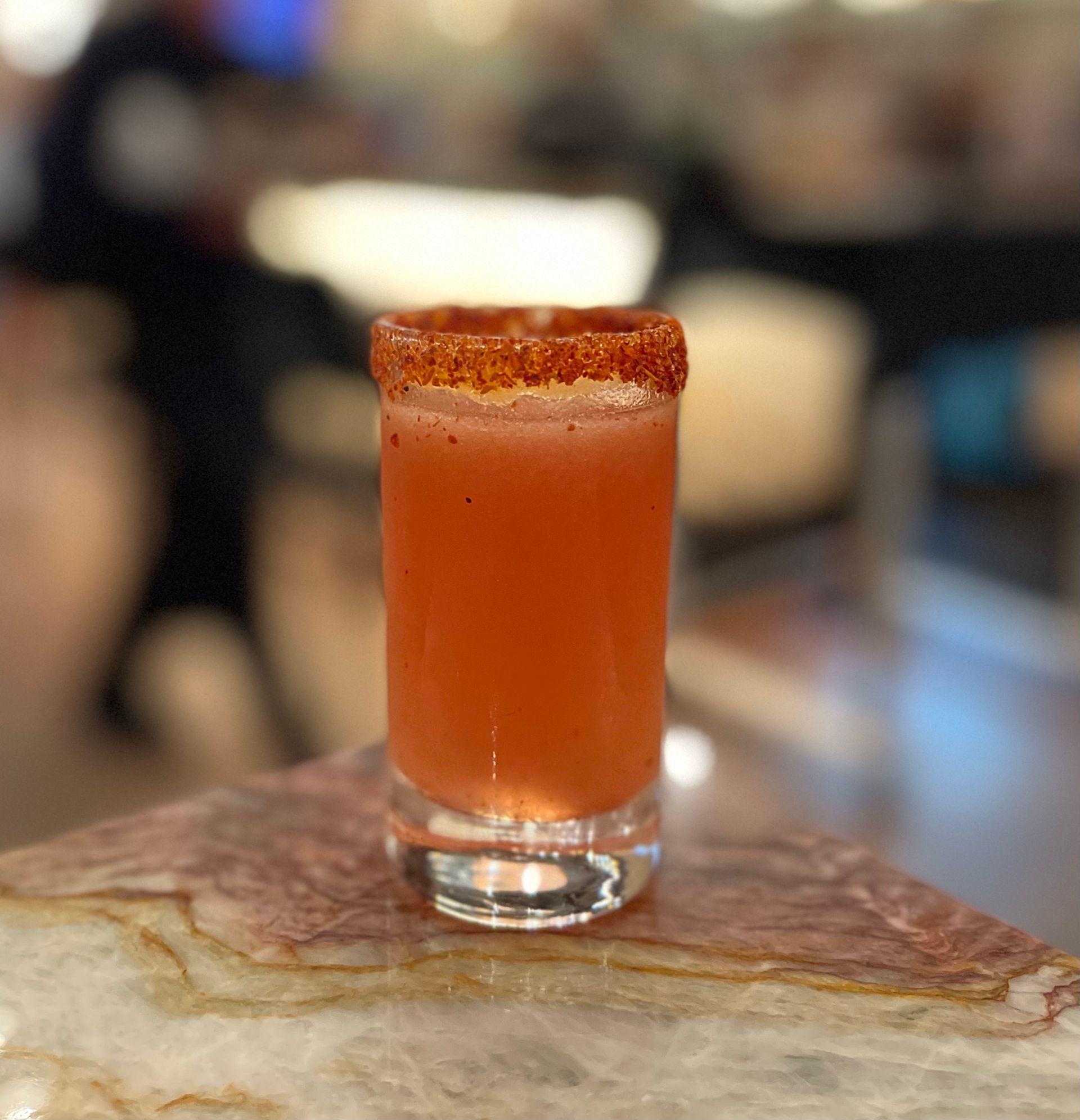 A shot glass filled with a red liquid on a table