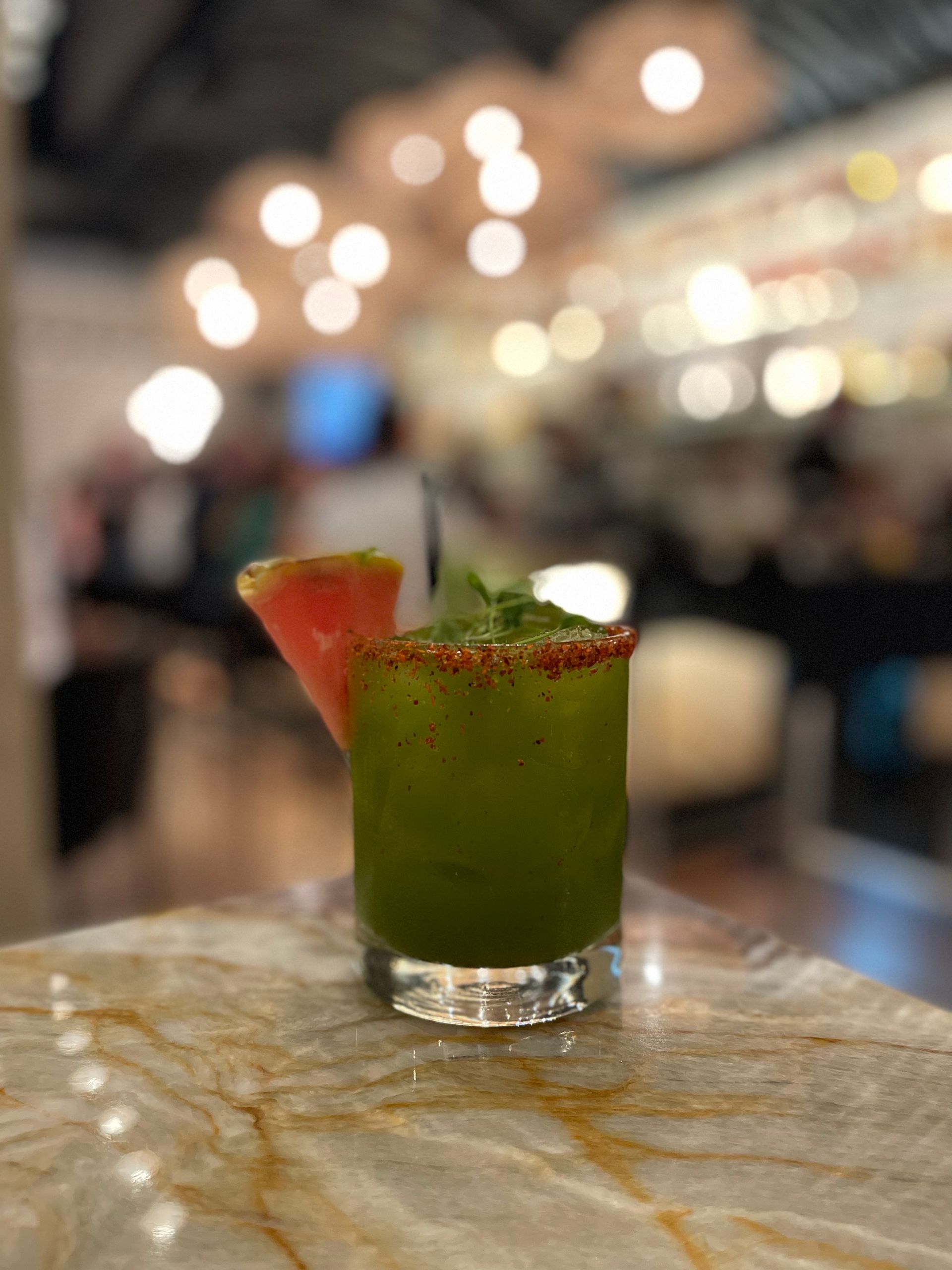 A green drink with a slice of watermelon on the rim