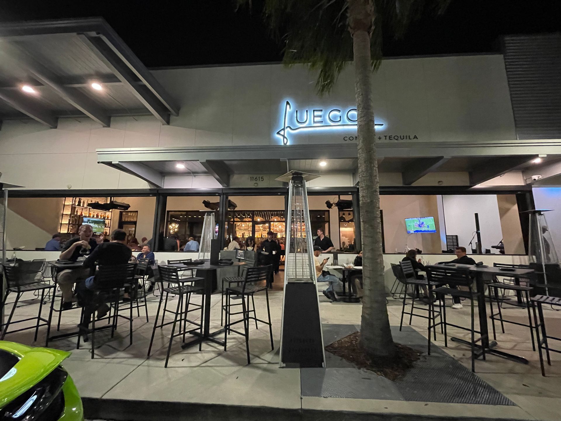 A group of people are sitting at tables outside of a restaurant.