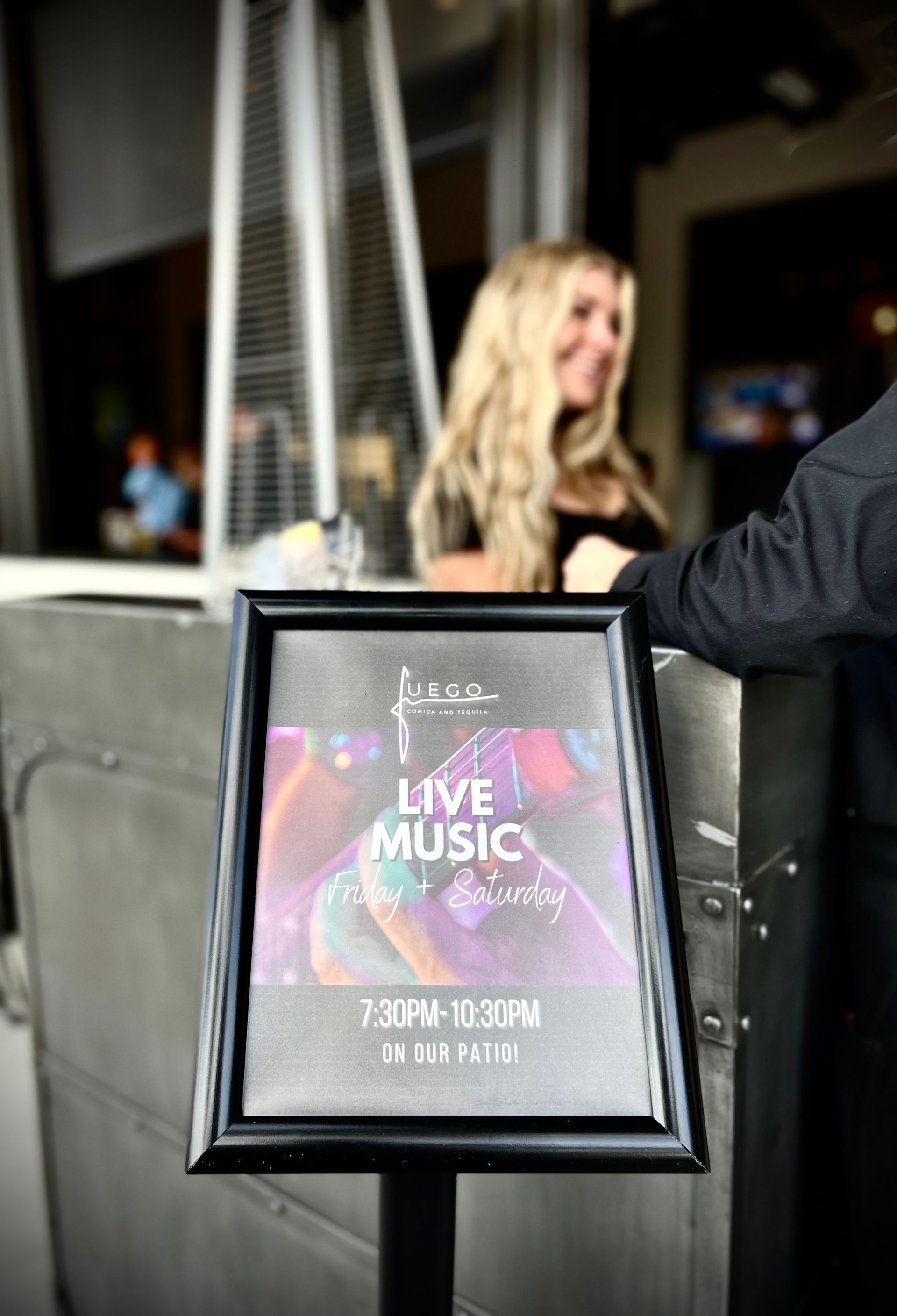 A woman is standing in front of a sign that says live music.