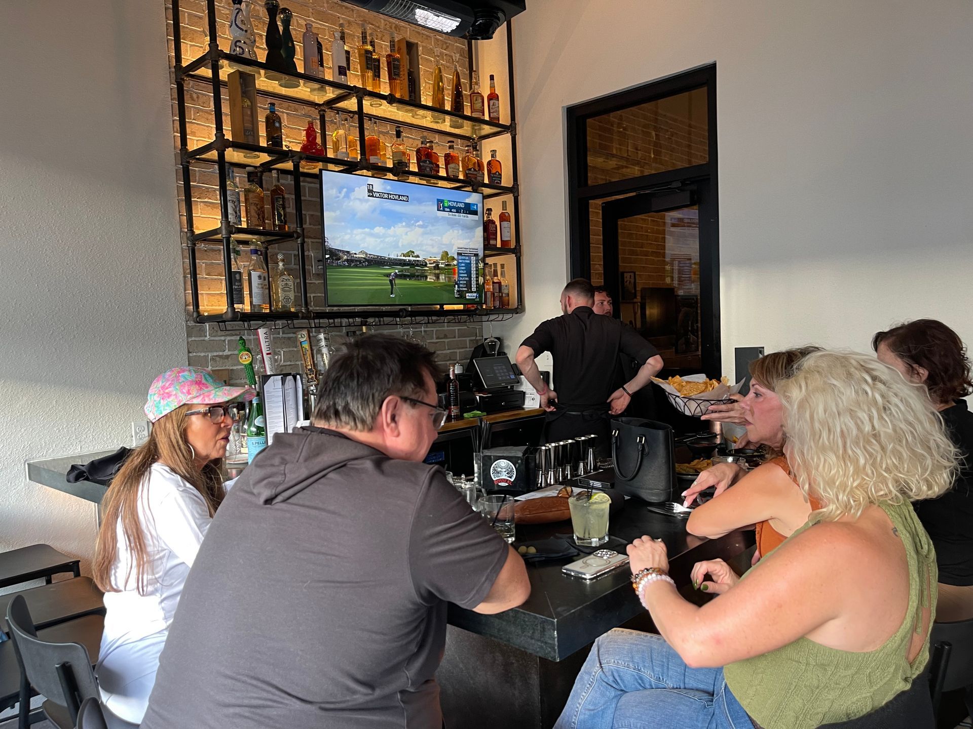 A group of people are sitting at a bar in a restaurant.