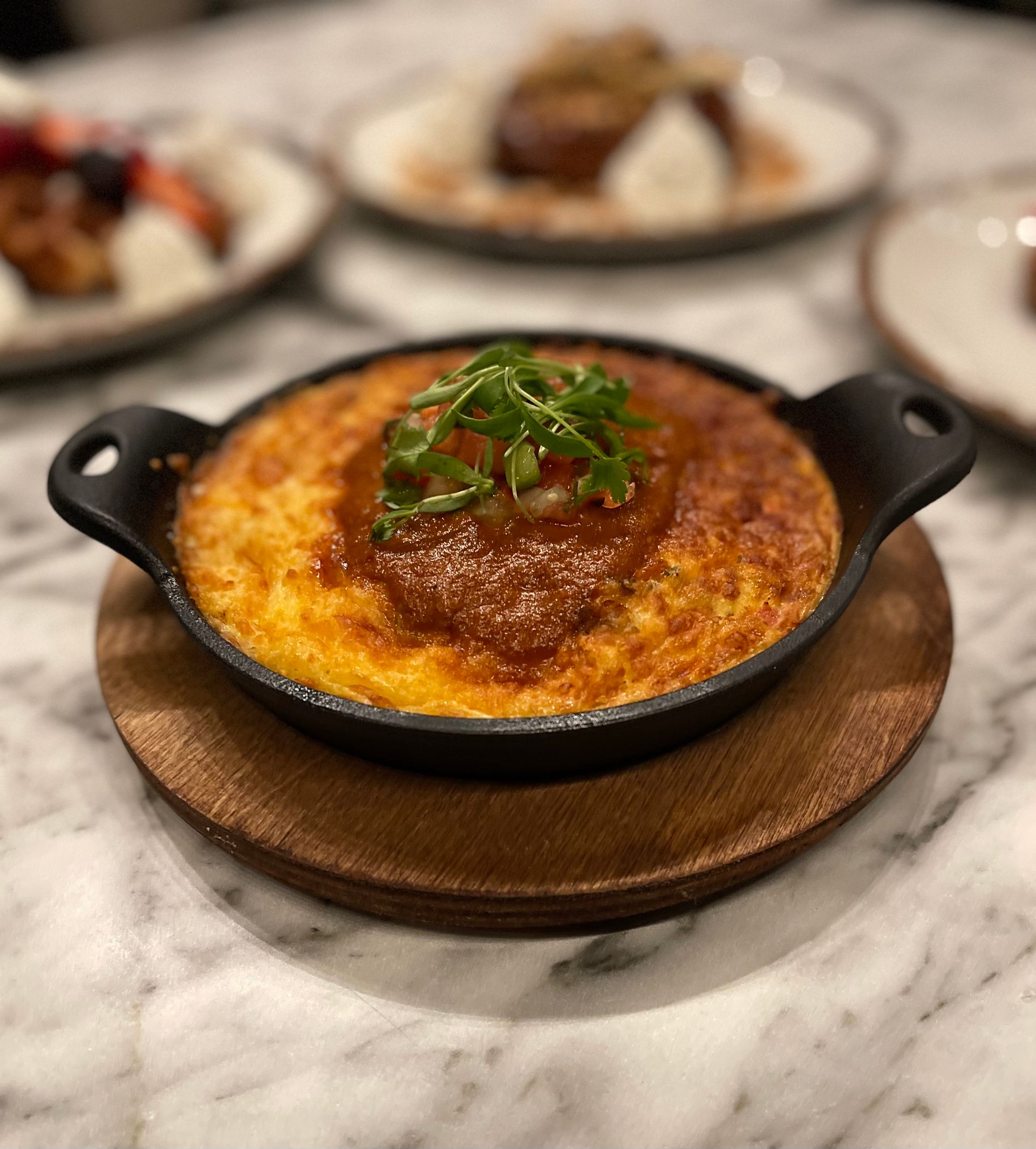 A close up of a bowl of food on a wooden plate on a table.