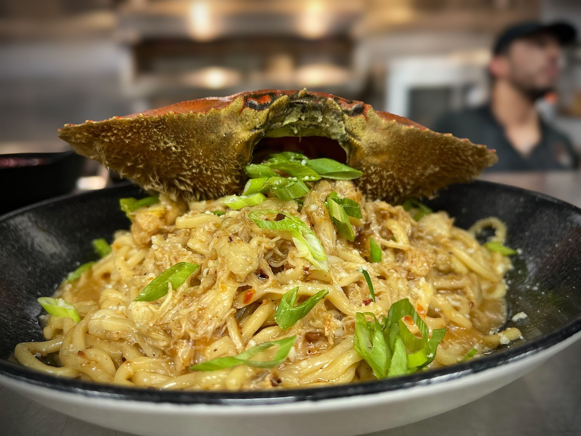 A bowl of noodles with a crab on top of it.