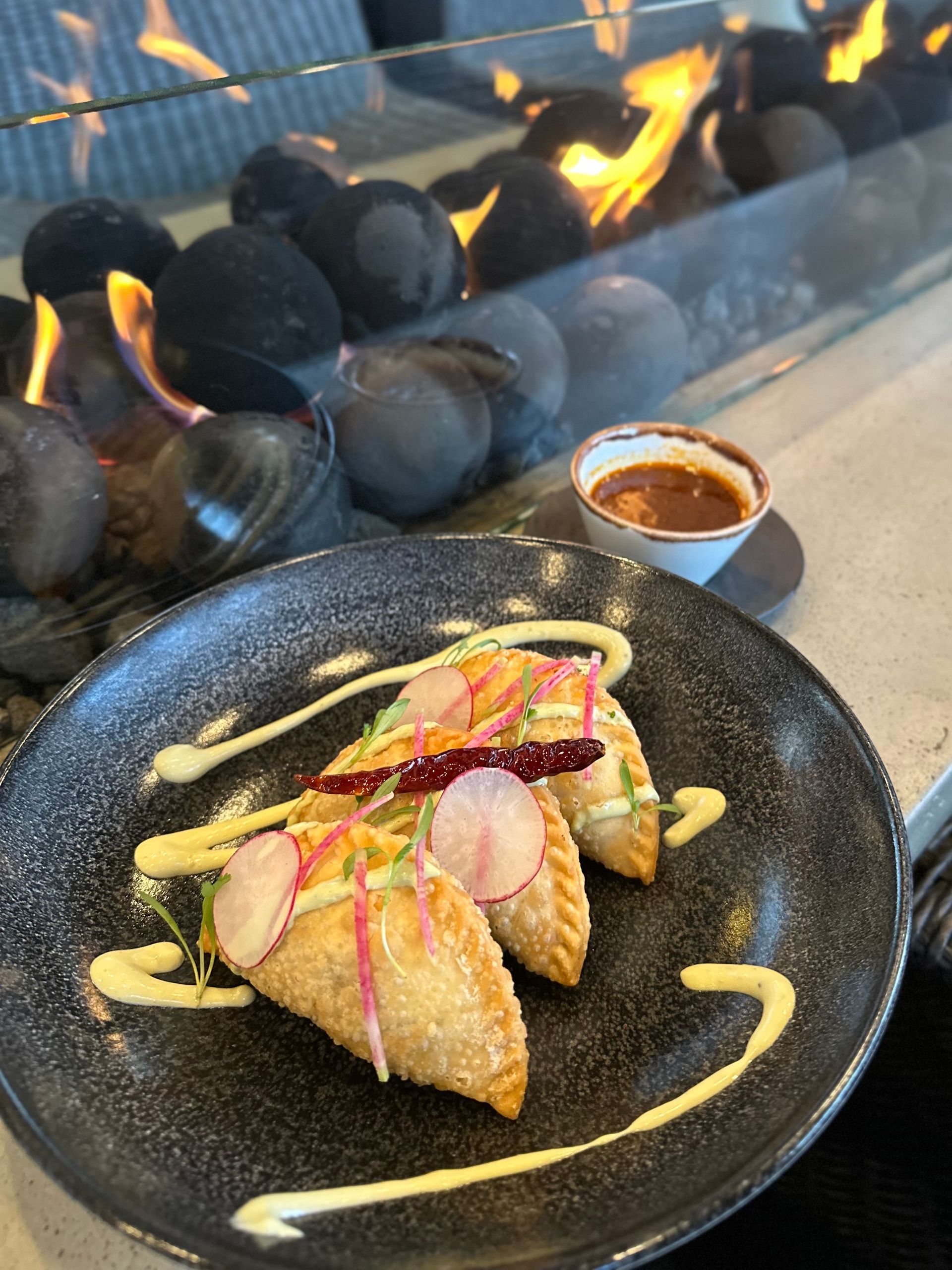 A plate of food is sitting in front of a fireplace.