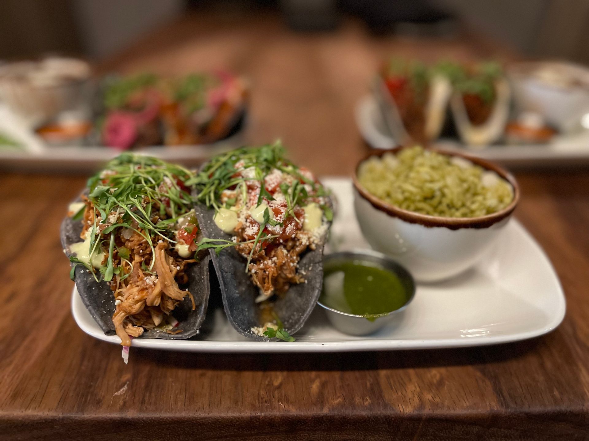 A white plate topped with two tacos and guacamole on a wooden table.