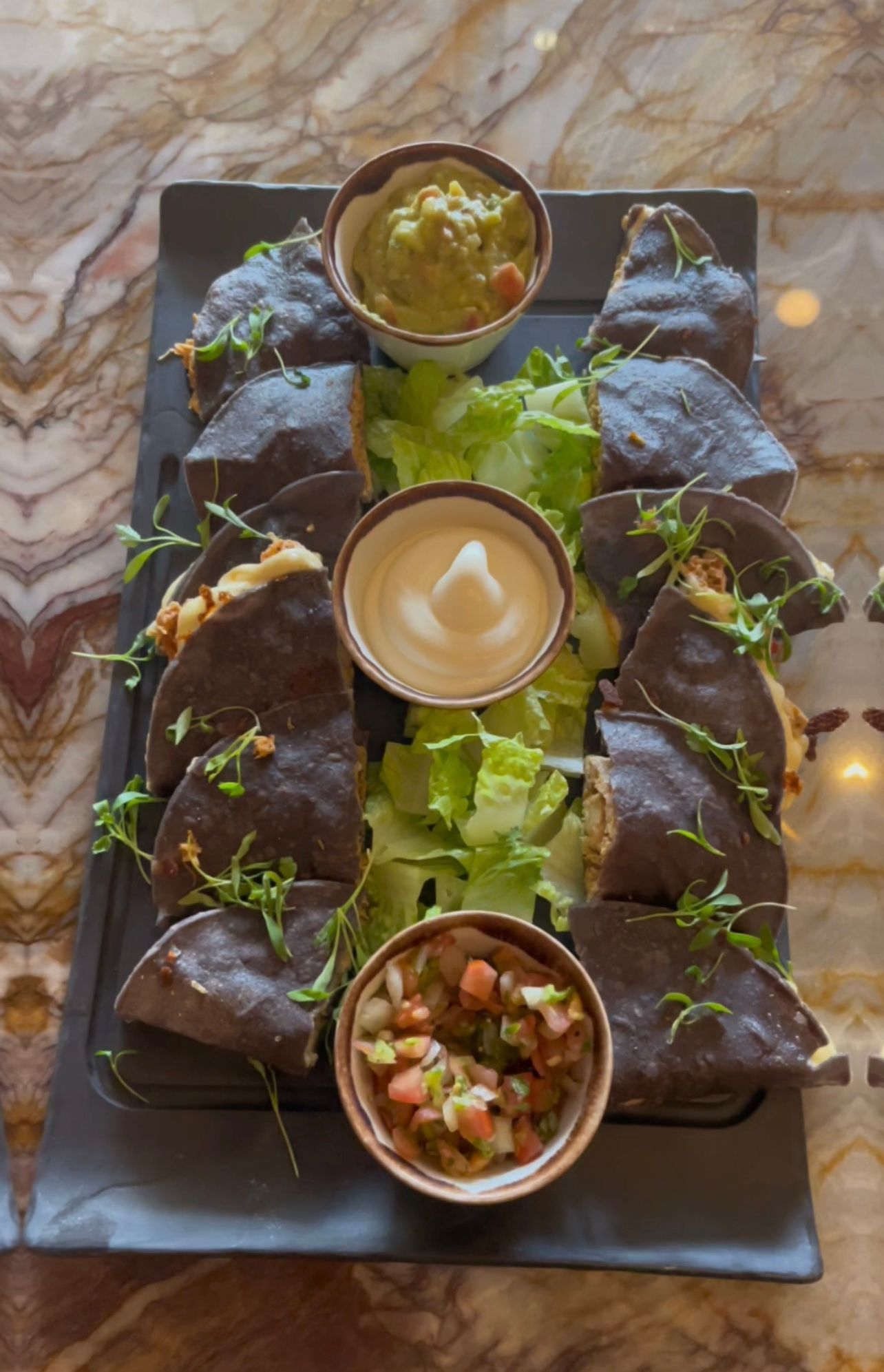 A plate of food with guacamole and salsa on a table.