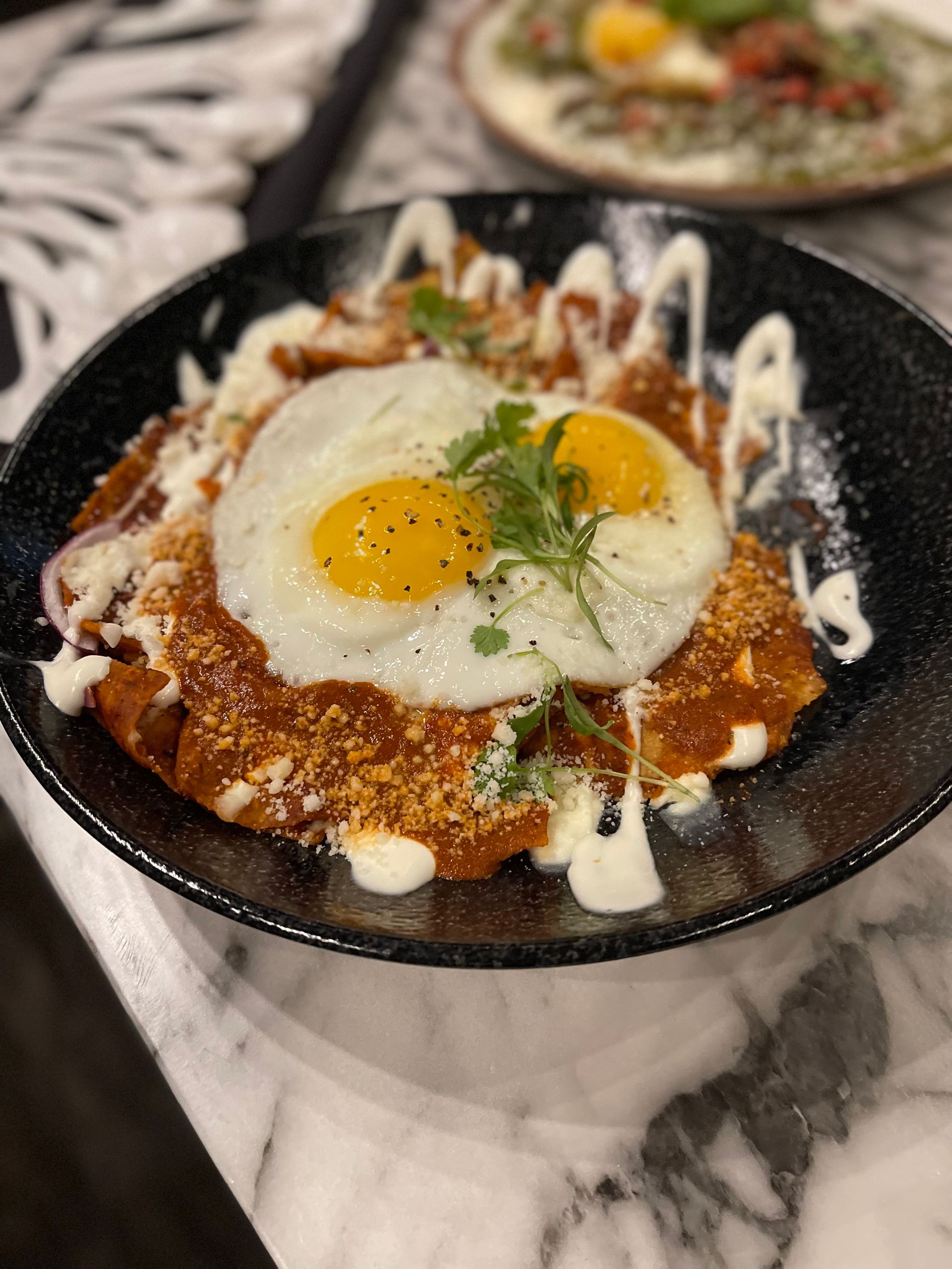 A close up of a plate of food with a fried egg on top on a table.