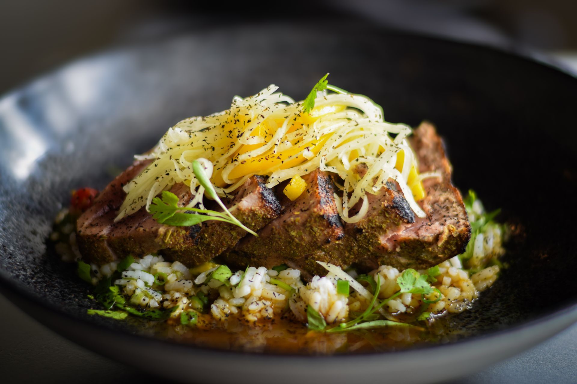 A close up of a plate of food with meat and rice on a table.