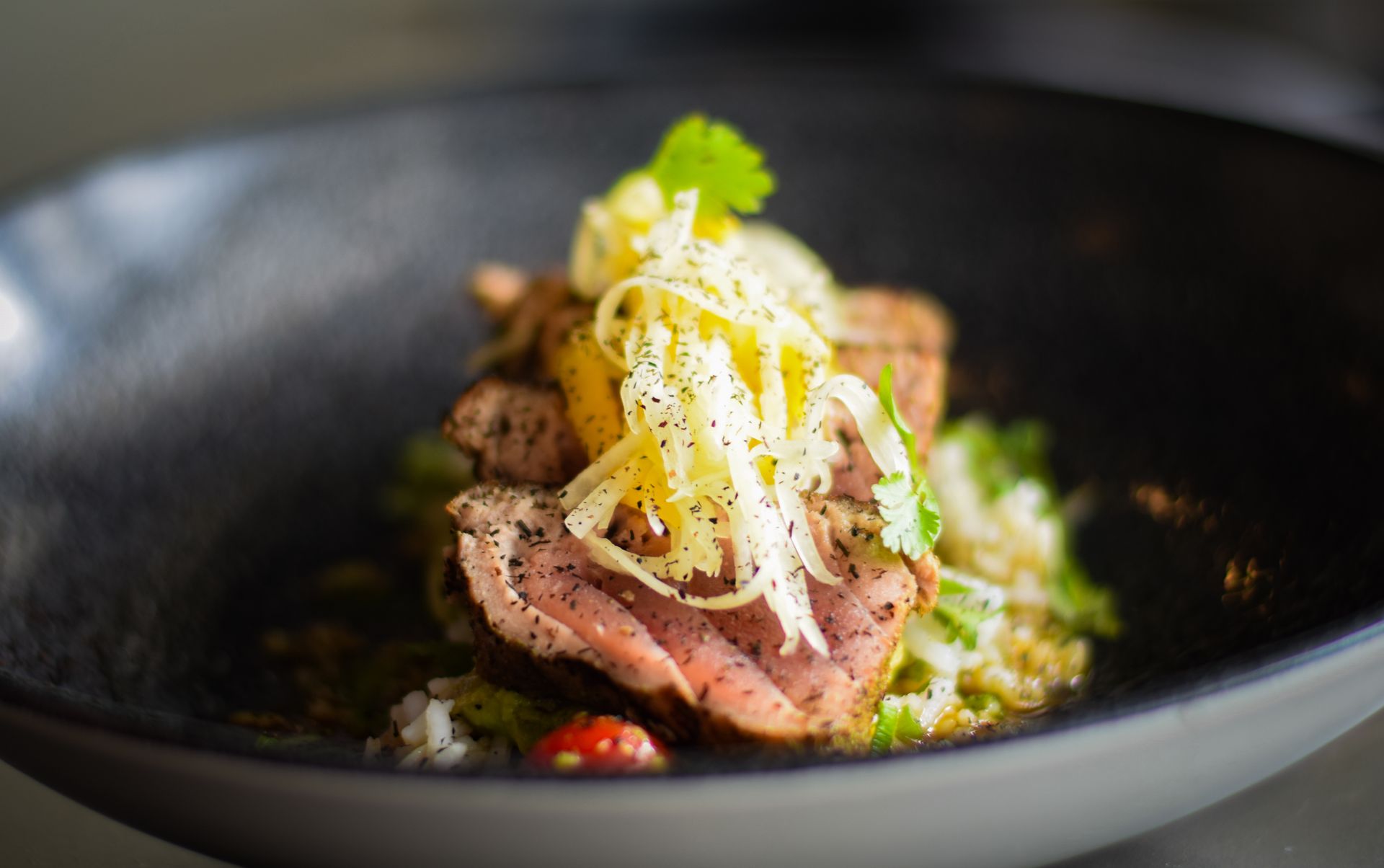 A close up of a plate of food with meat and vegetables on a table.