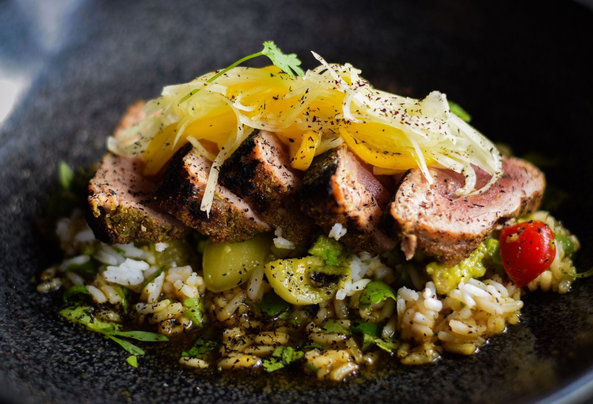 A close up of a plate of food with meat and rice on a table.
