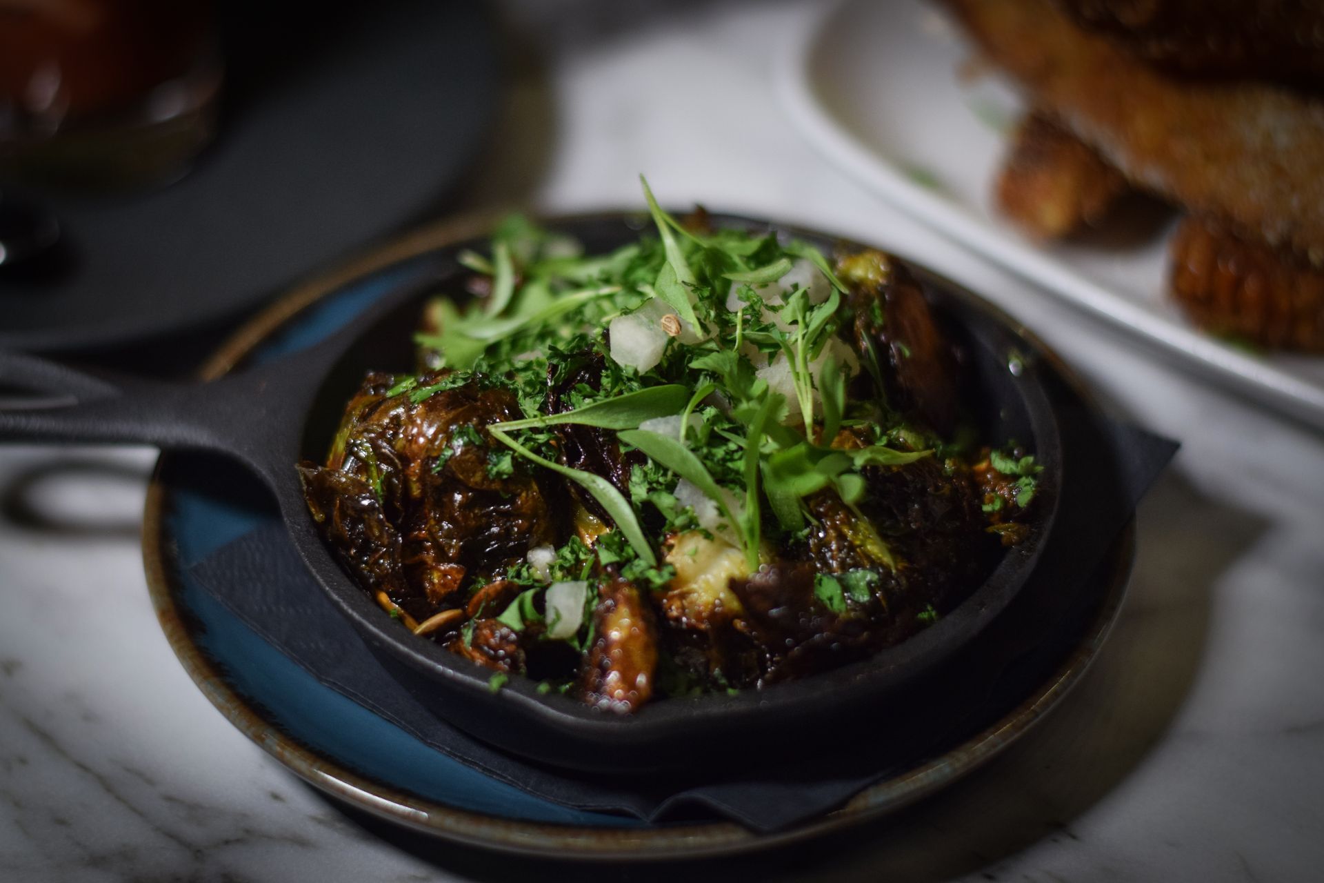 A skillet filled with food is on a plate on a table.