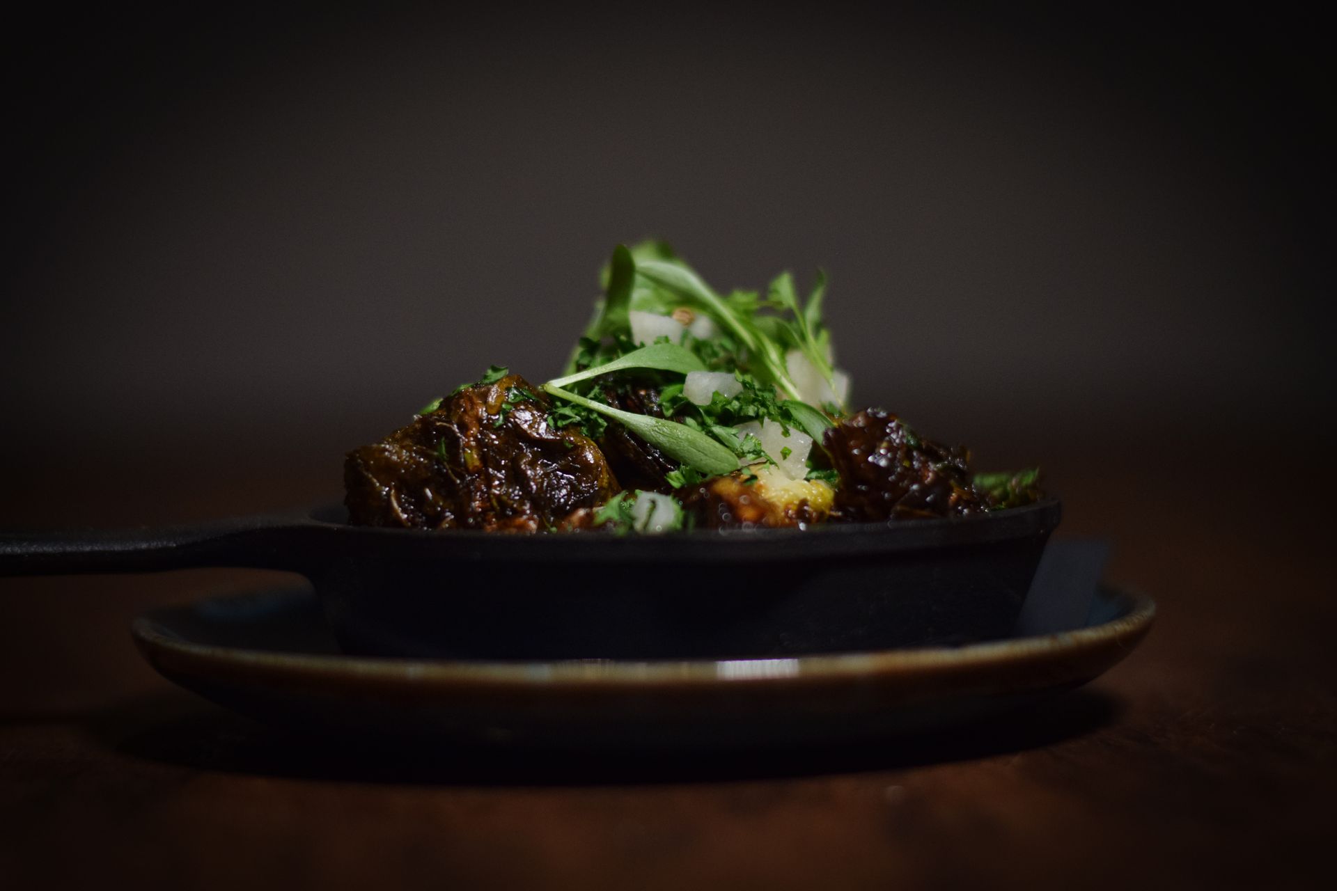 A pan filled with meat and vegetables is on a plate on a table.
