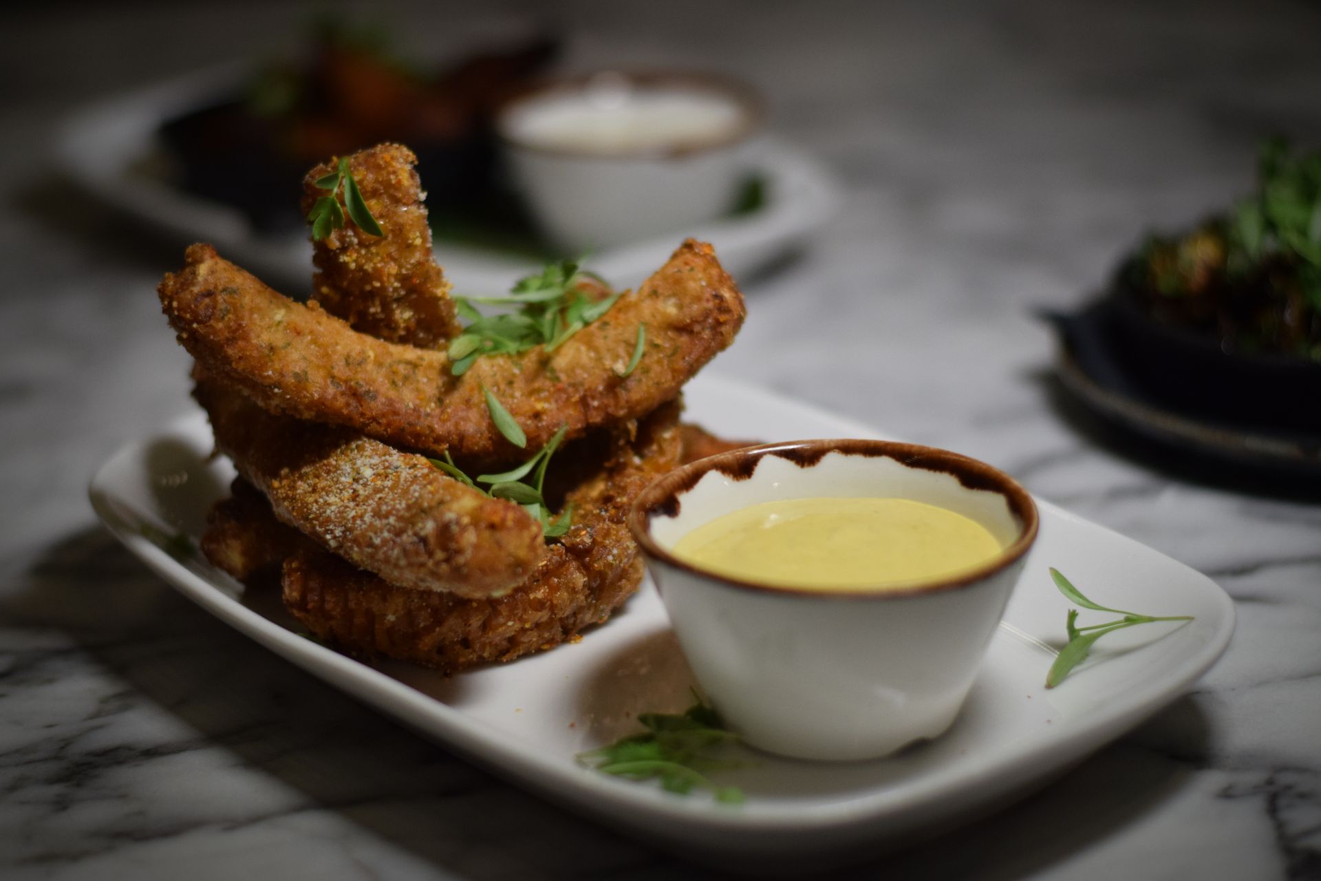 A white plate topped with fried chicken and a bowl of dipping sauce.