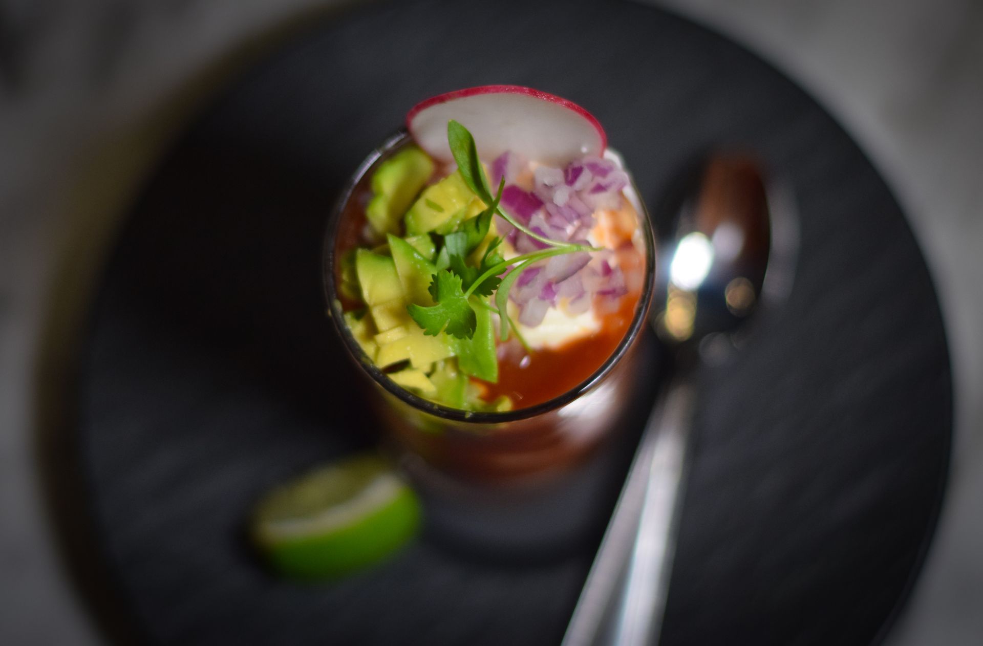 A close up of a drink in a glass with a spoon on a plate.