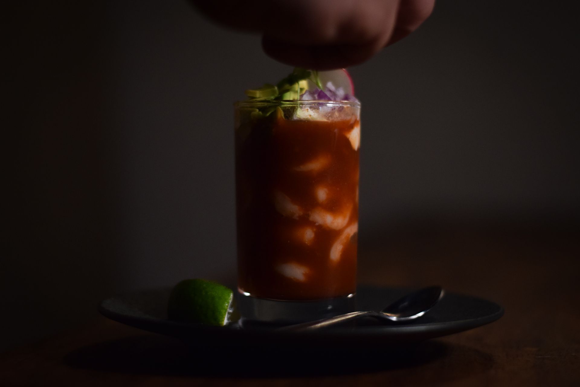 A person is pouring a drink into a glass on a plate.