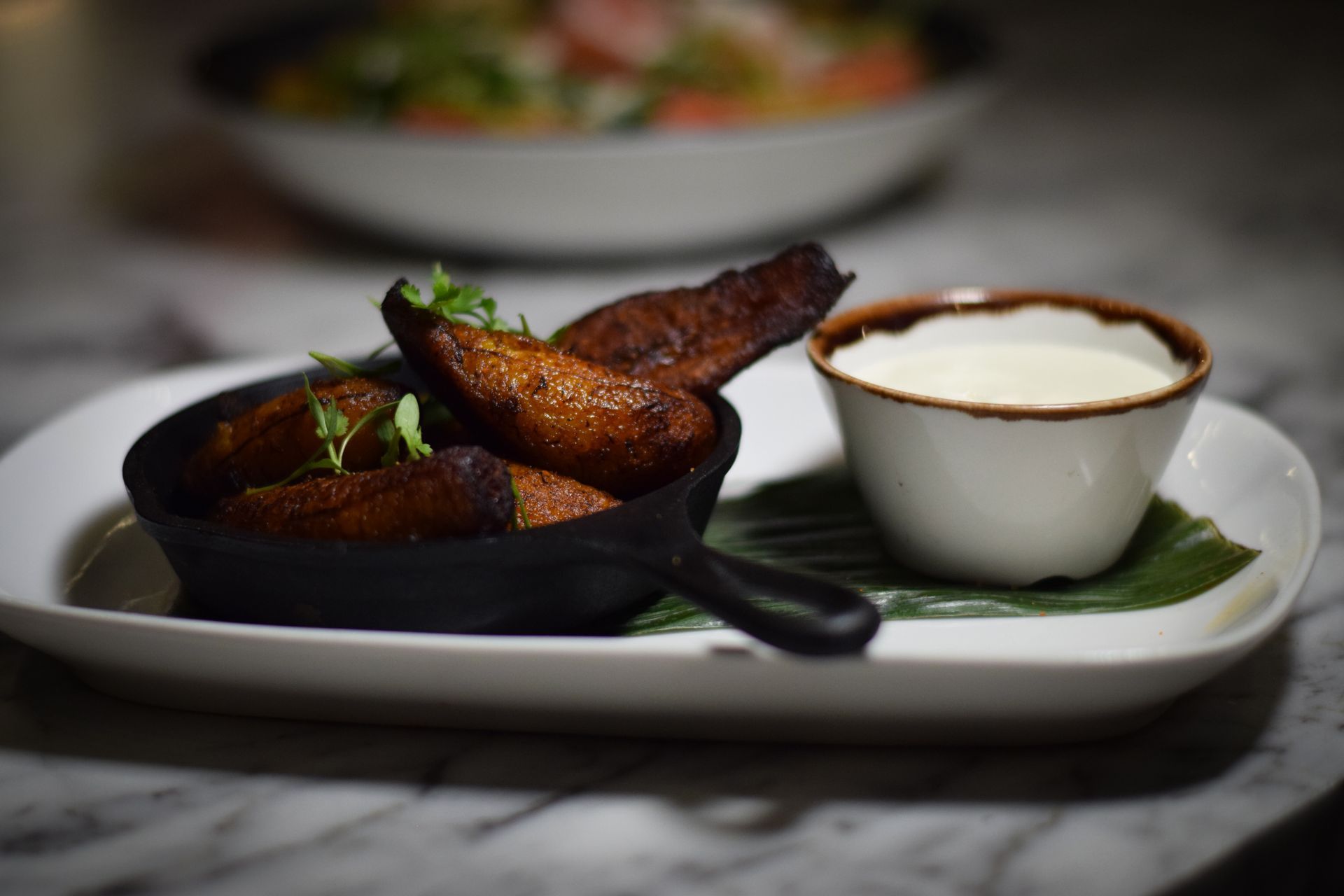 A plate of food with a bowl of sour cream on a table.