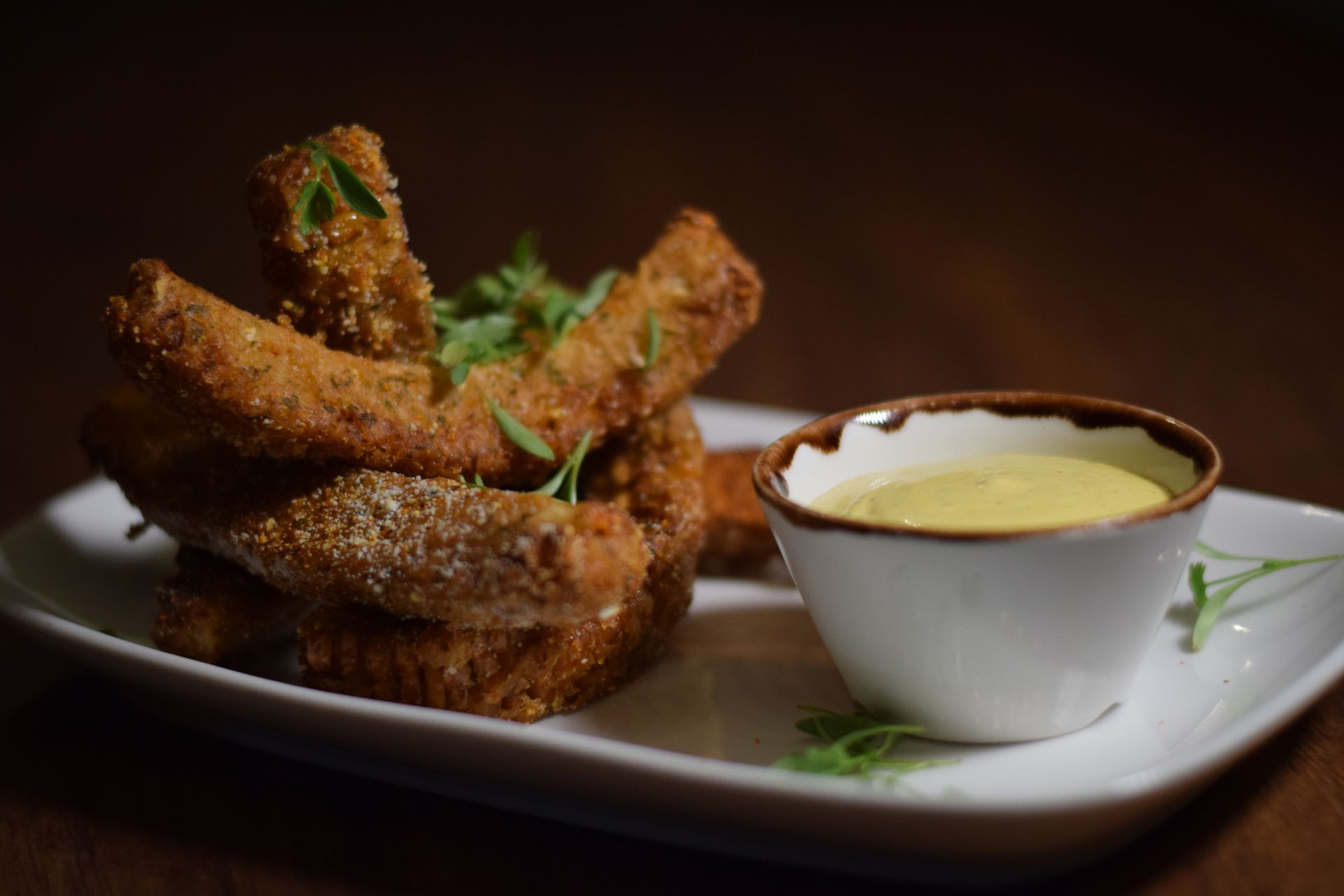 A white plate topped with fried food and a bowl of dipping sauce.