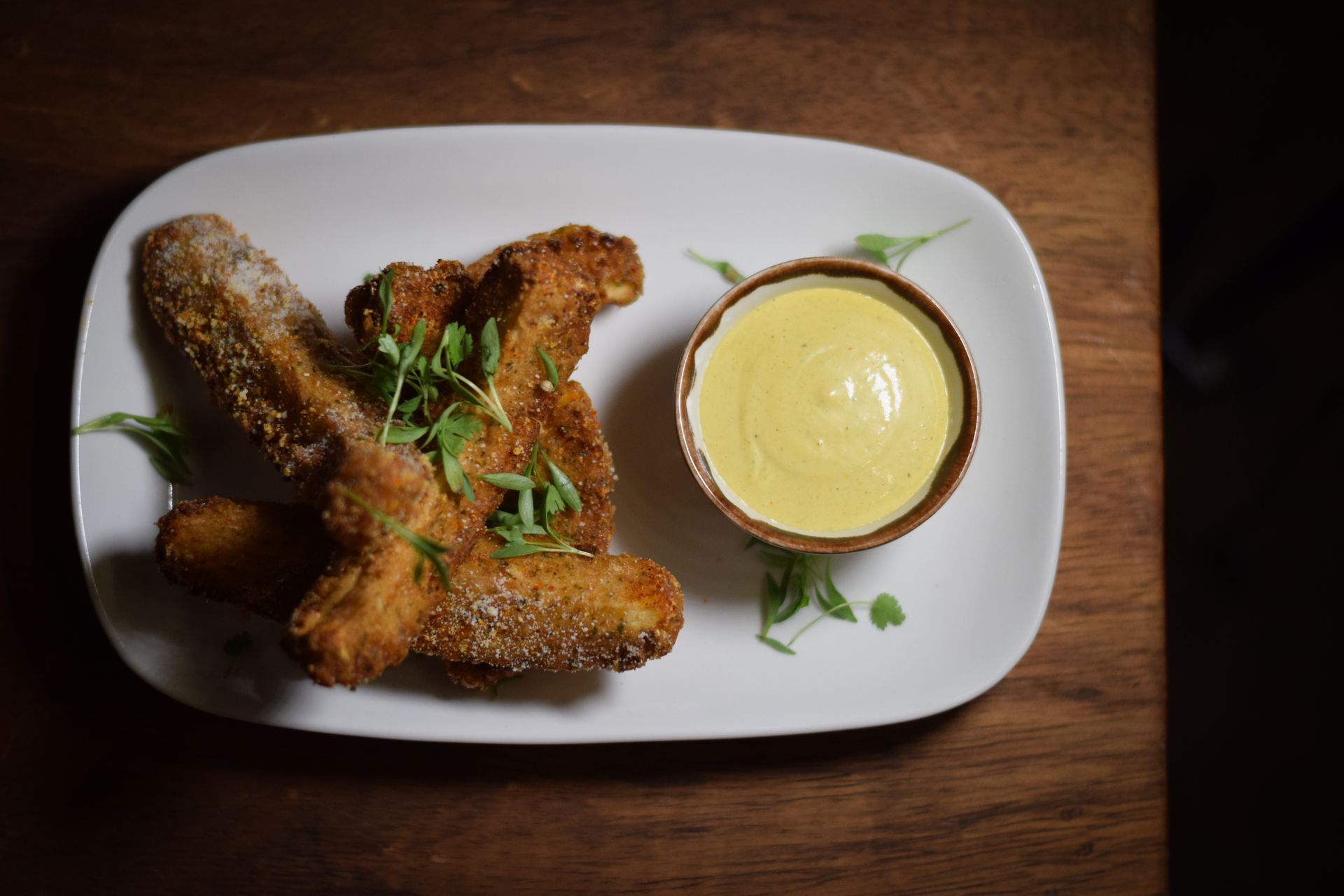 A white plate topped with fried food and a bowl of dipping sauce.