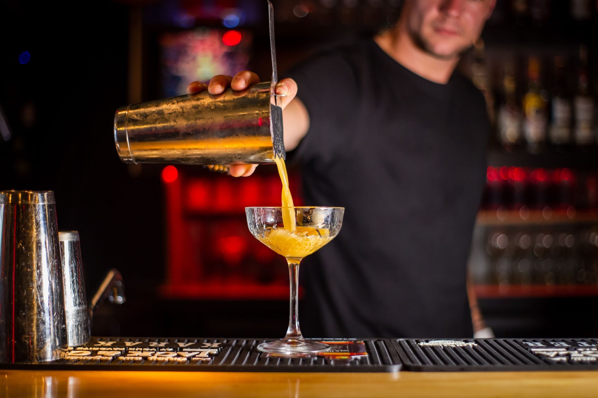 A bartender is pouring a drink into a glass at a bar.