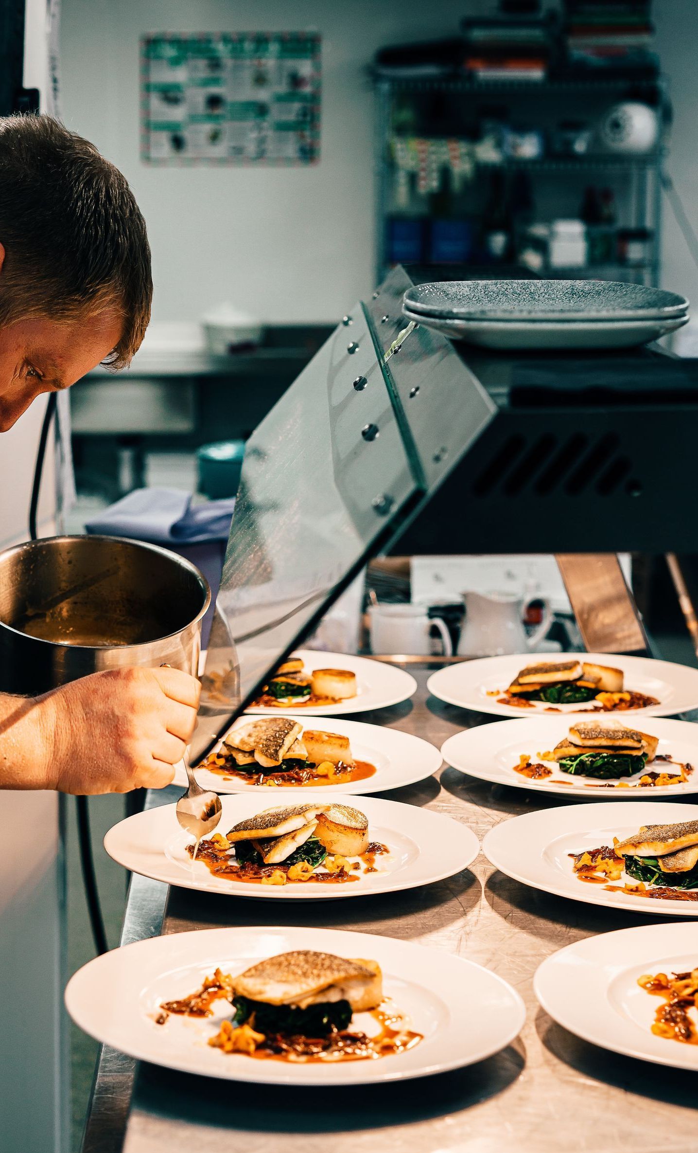 A man is preparing food in a kitchen with plates of food on a table.