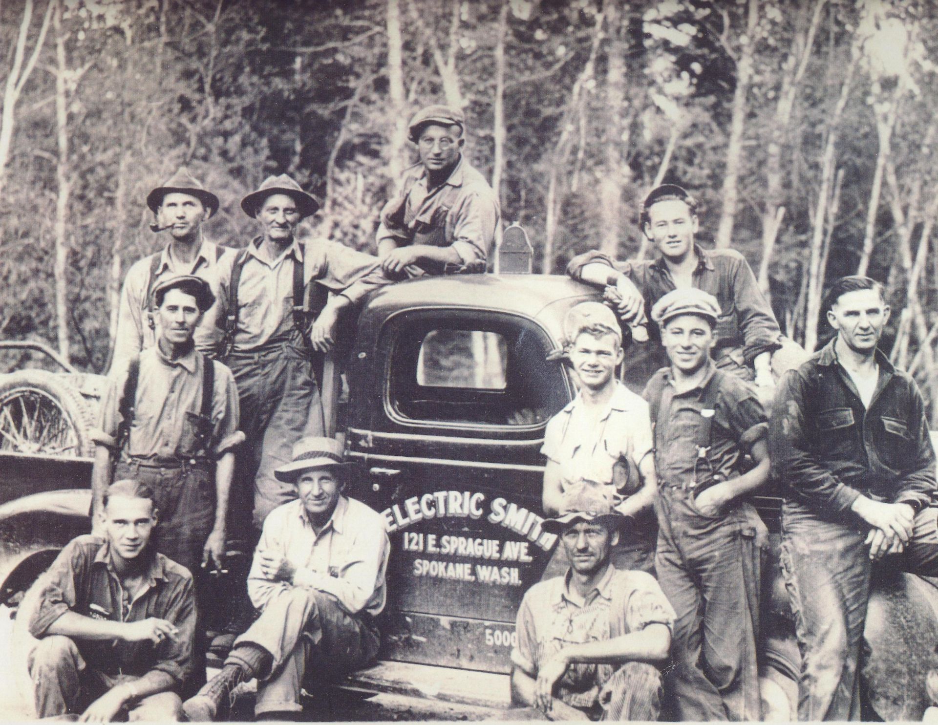 A group of men posing with a vintage truck labeled Electric Smith.