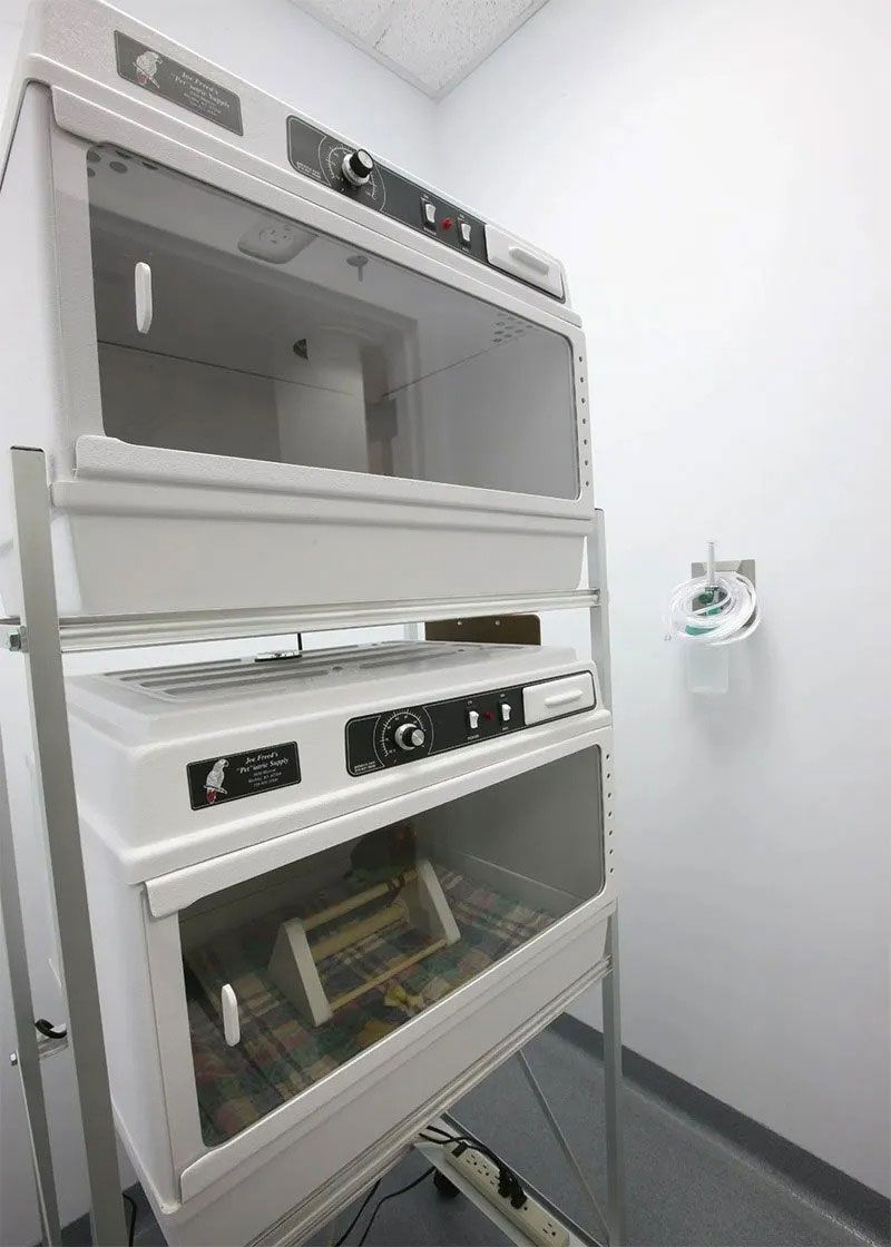 Industrial lab equipment in a white room, with stacked glass-fronted chambers and control panels.