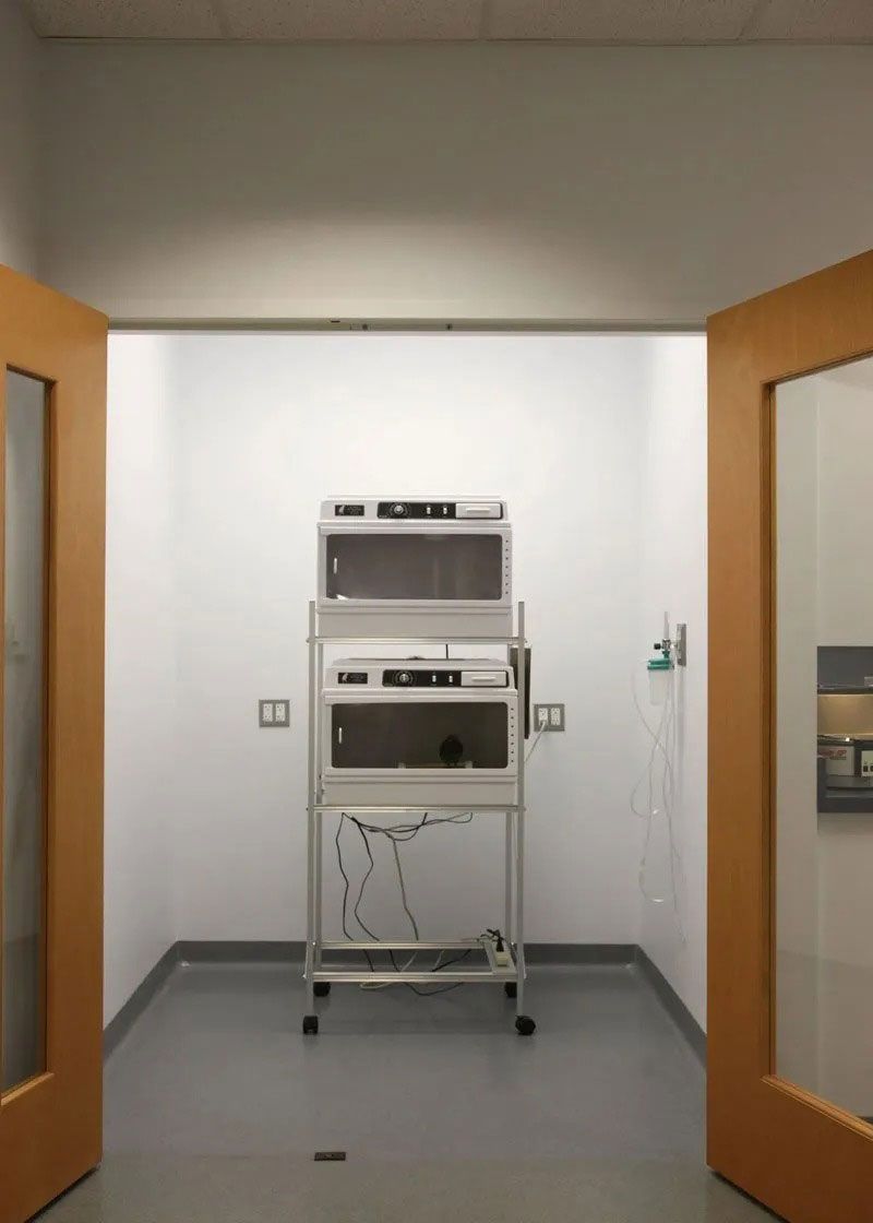 Hospital room with open doors and a medical machine on a wheeled stand in the center