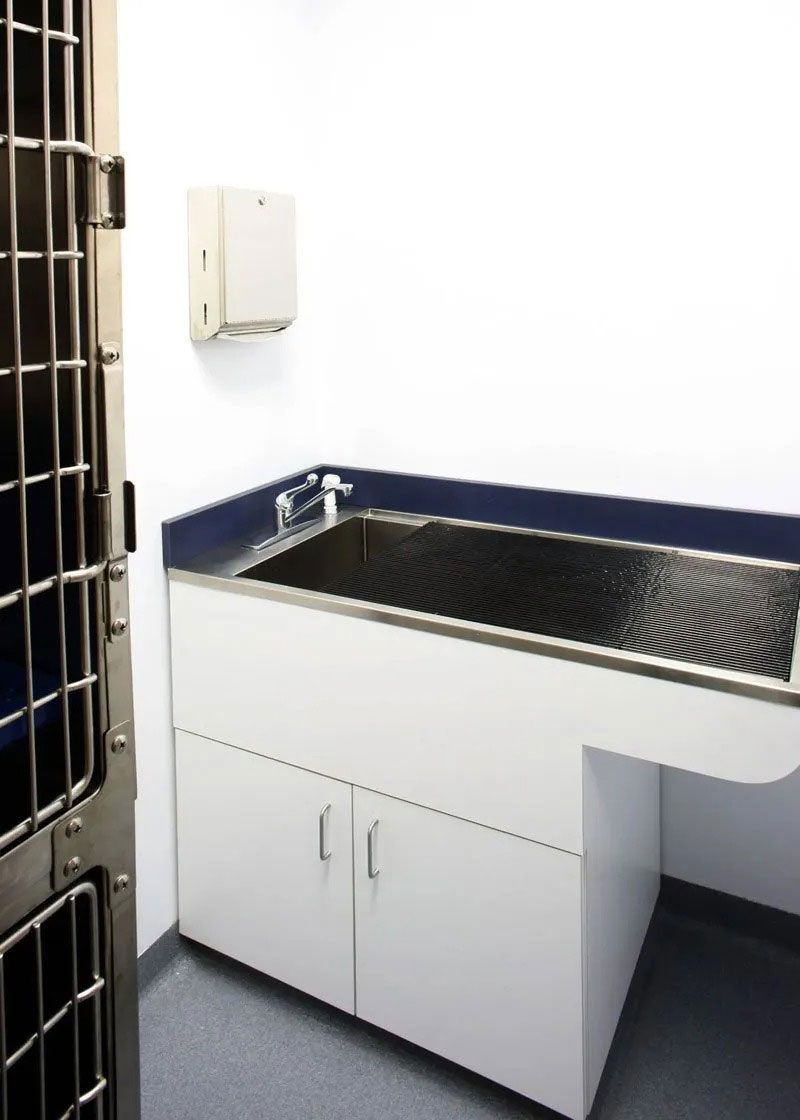 Utility sink and cabinet in a small room with white walls and a tiled floor