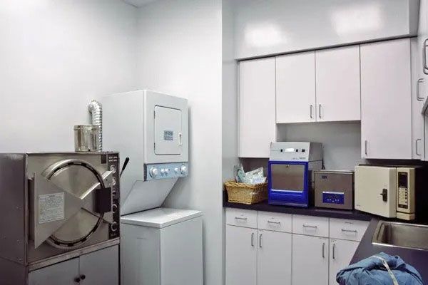 Industrial laundry room with white cabinets, washer, dryer, and stainless steel machines