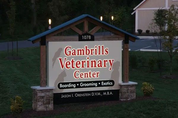 Sign for Gambrills Veterinary Center at dusk, with boarded services listed and a house number above.